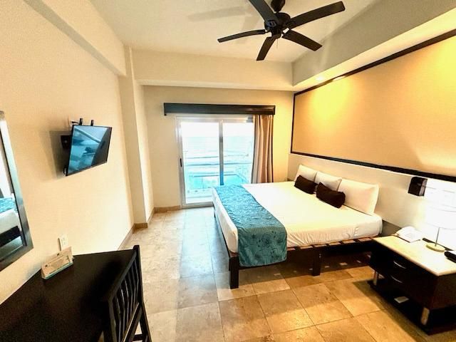 Una habitación de hotel con una cama tamaño king y un televisor de pantalla plana.