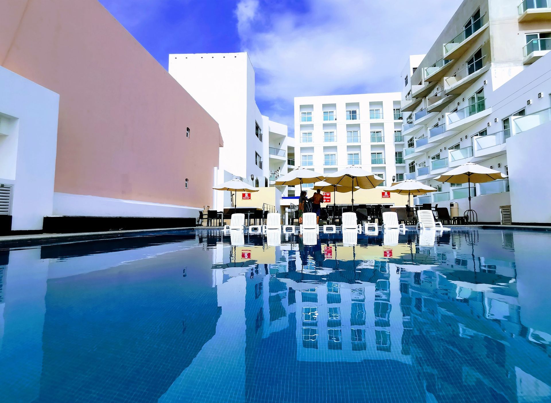 A large swimming pool surrounded by buildings and umbrellas
