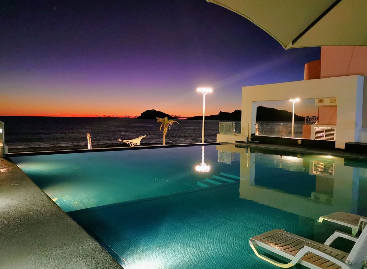 Una gran piscina con vista al mar por la noche.