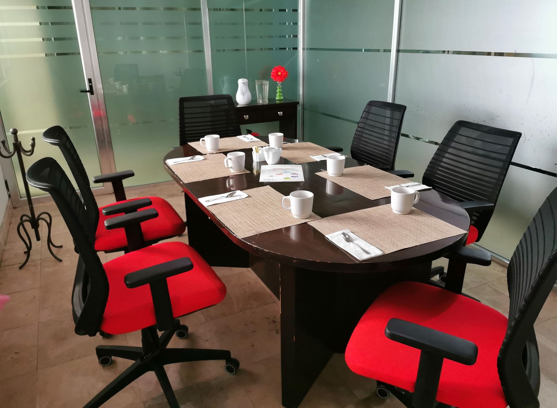 Una sala de conferencias con una mesa y sillas preparadas para una reunión.