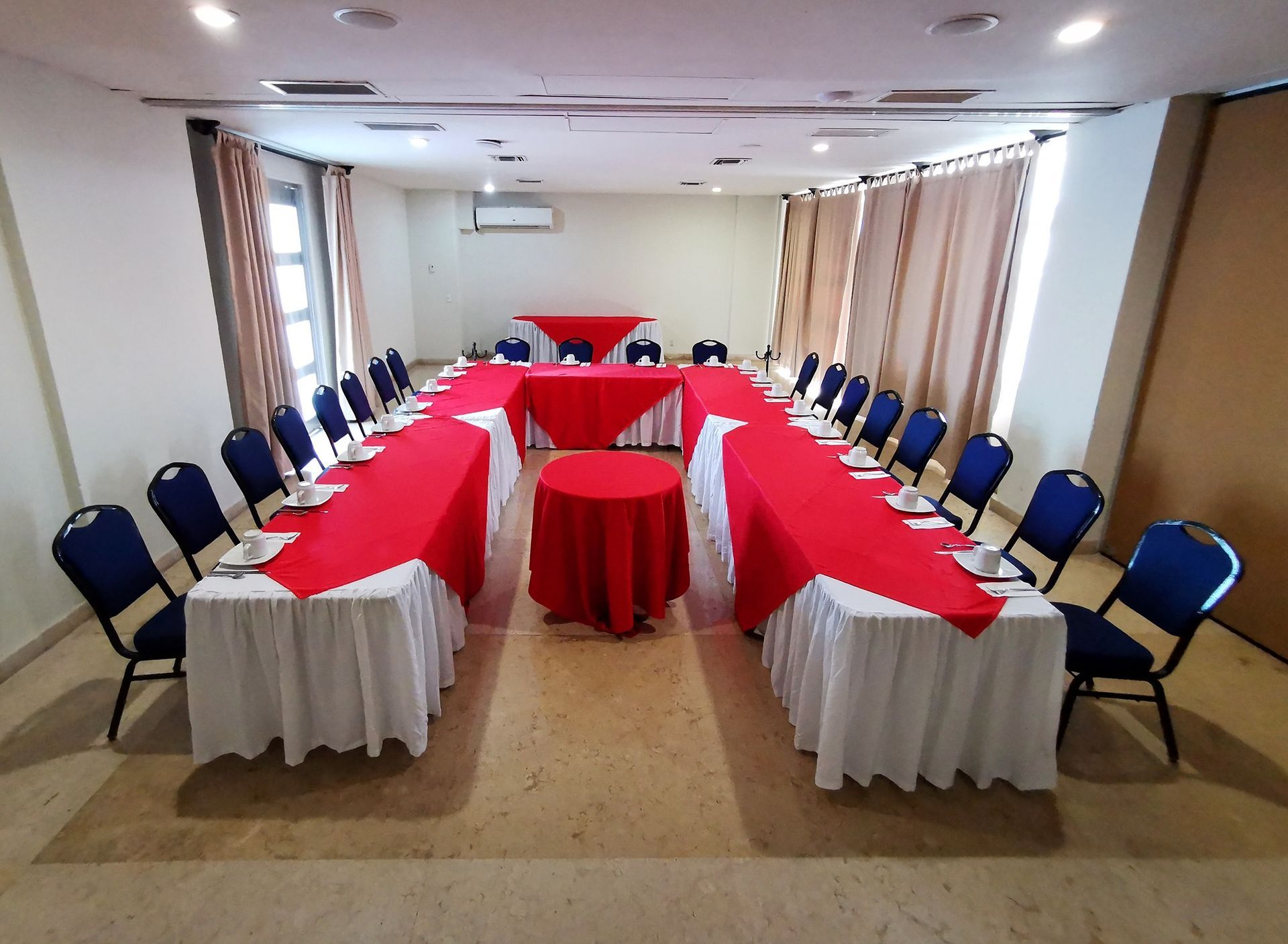 Una sala grande con mesas y sillas preparadas para una reunión.