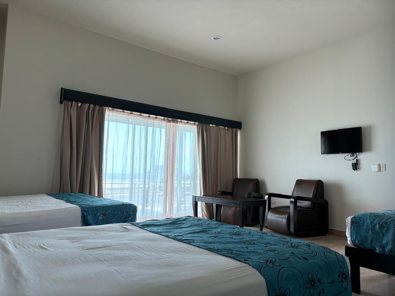 Una habitación de hotel con dos camas, dos sillas y un televisor.