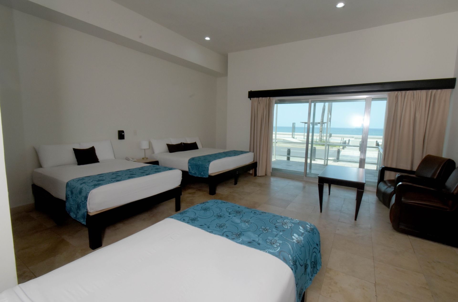 Una habitación de hotel con dos camas y una puerta corrediza de vidrio.