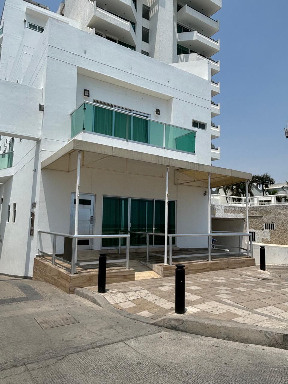 Un edificio blanco con balcón y cortinas verdes.