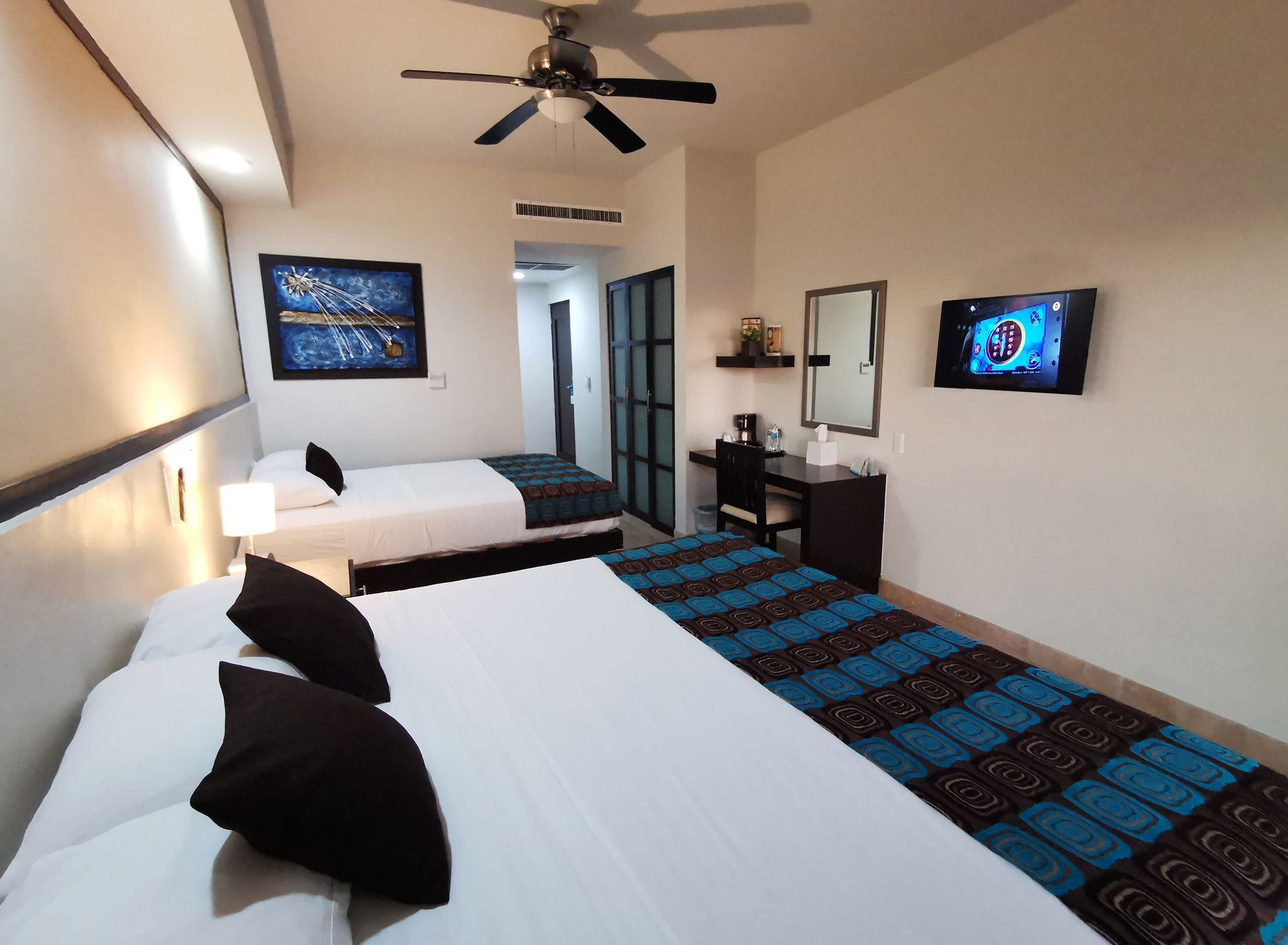 Una habitación de hotel con dos camas y un ventilador de techo.