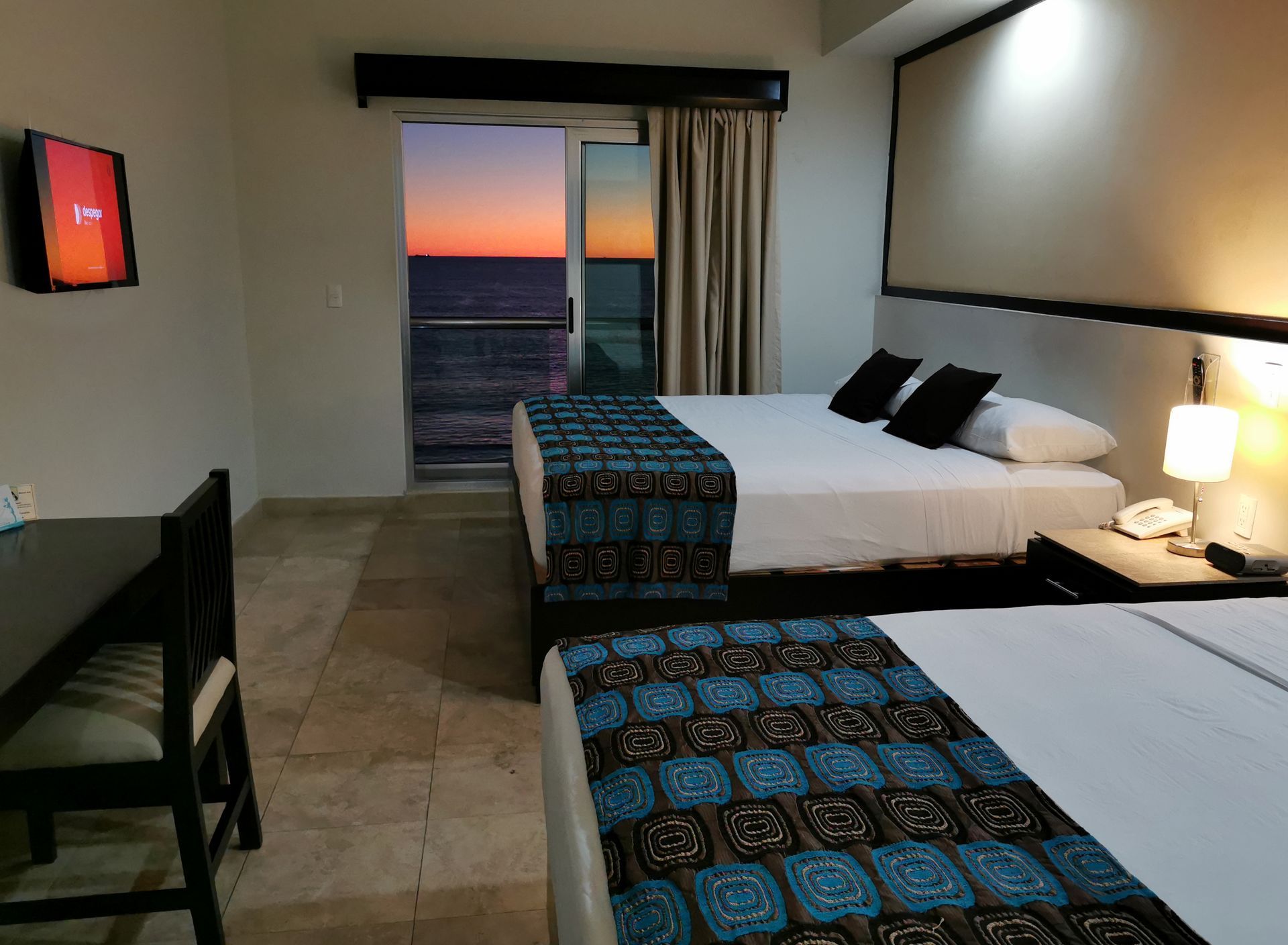 Una habitación de hotel con dos camas, un escritorio y un televisor.