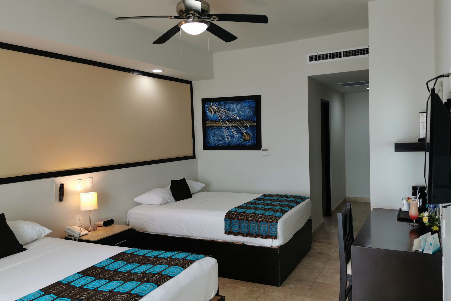 Una habitación de hotel con dos camas y un ventilador de techo.
