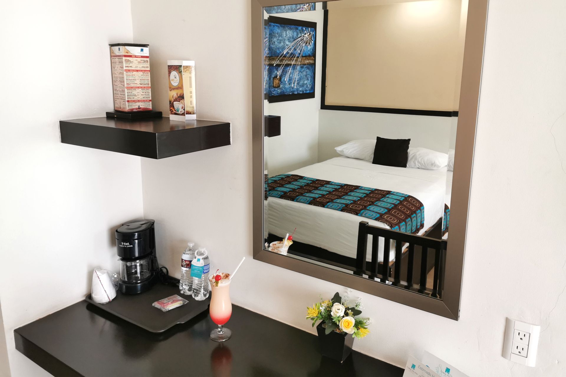 Una habitación de hotel con una cama y un escritorio con una bebida encima.