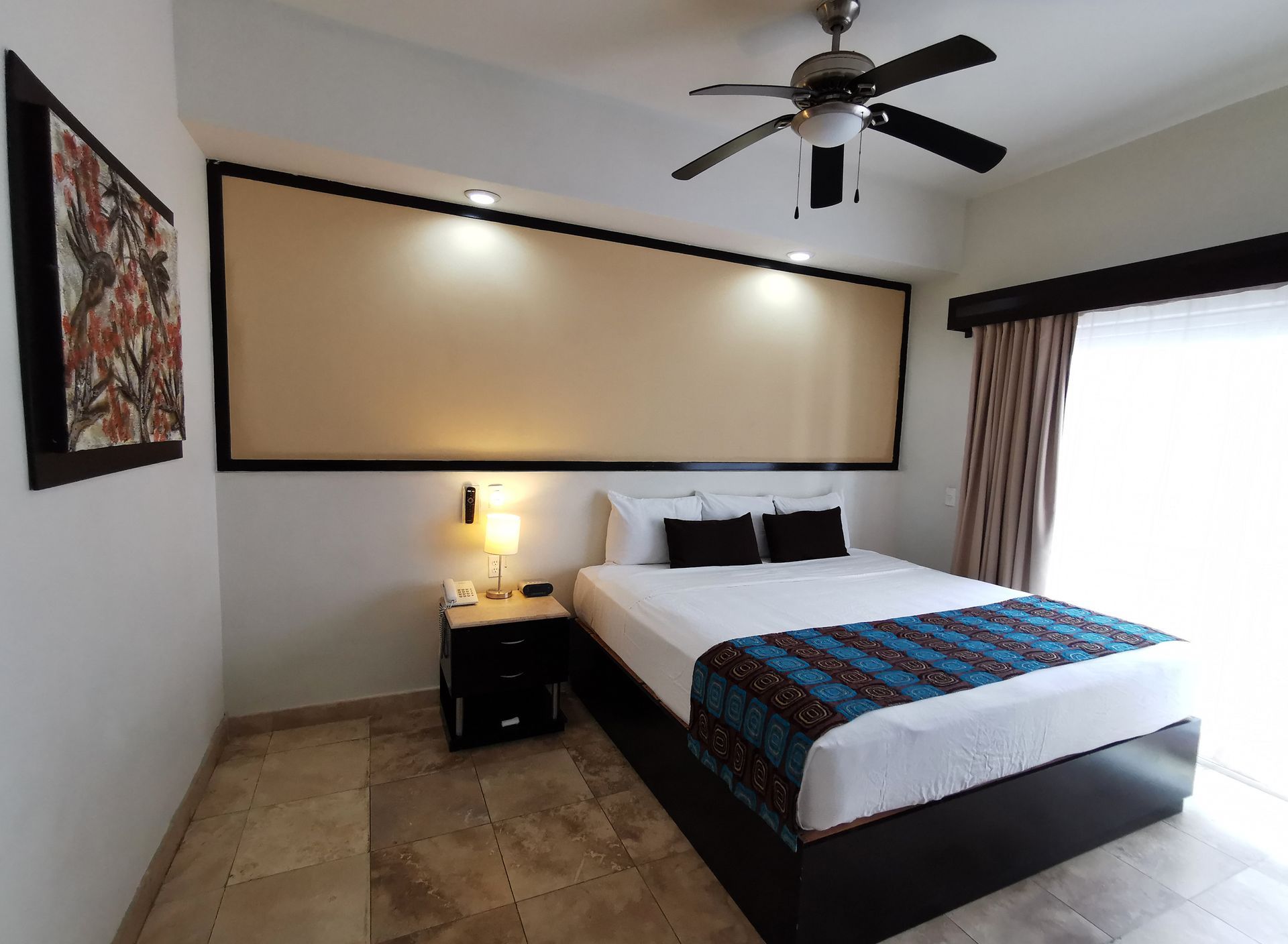 Una habitación de hotel con una cama tamaño king y un ventilador de techo.