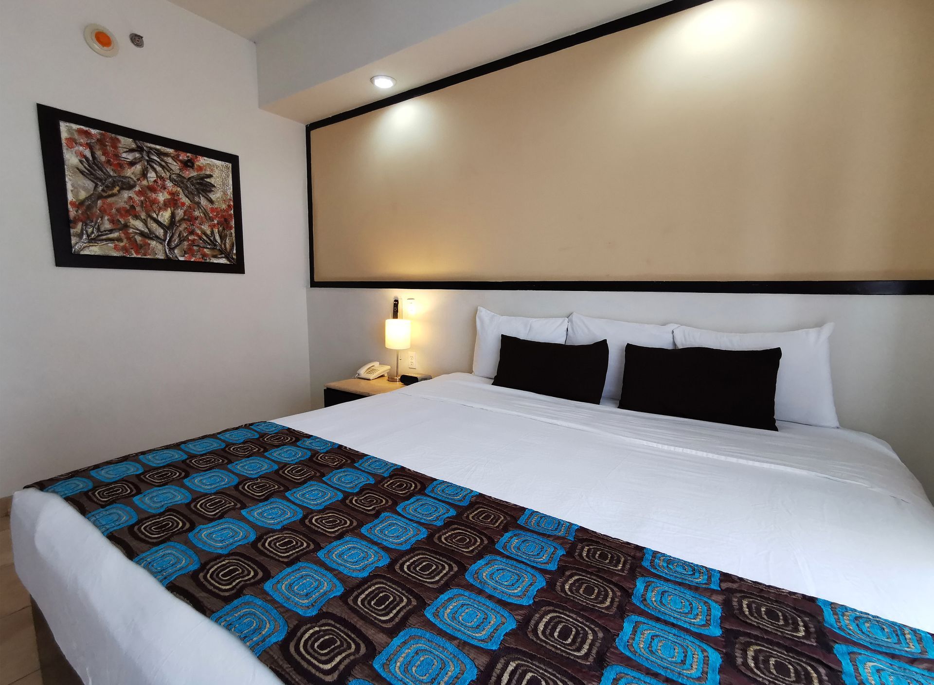 Una habitación de hotel con una cama y un cuadro en la pared.