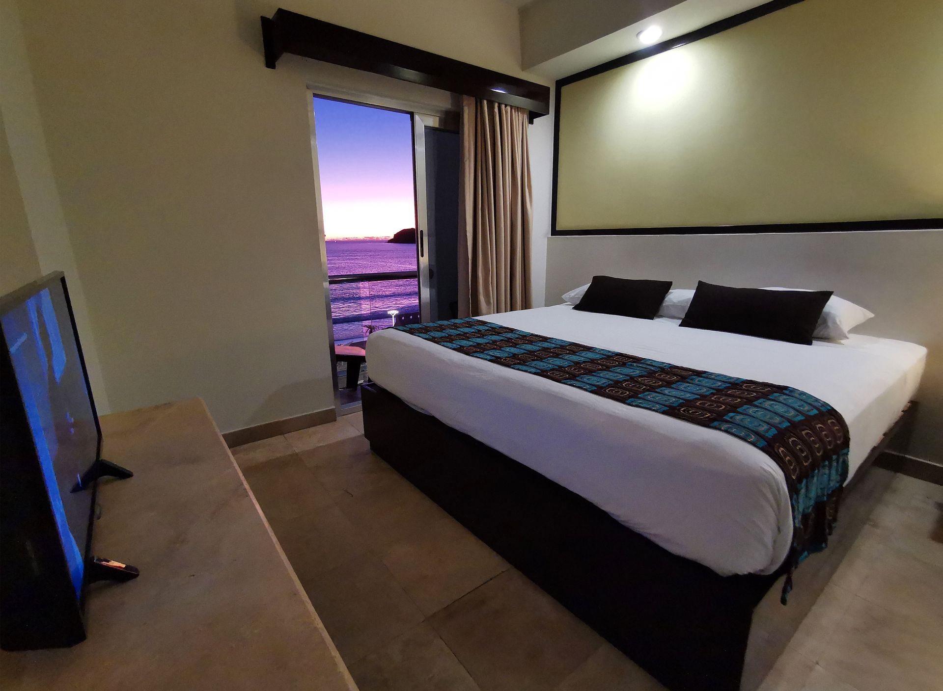 Una habitación de hotel con una cama grande y un televisor de pantalla plana.