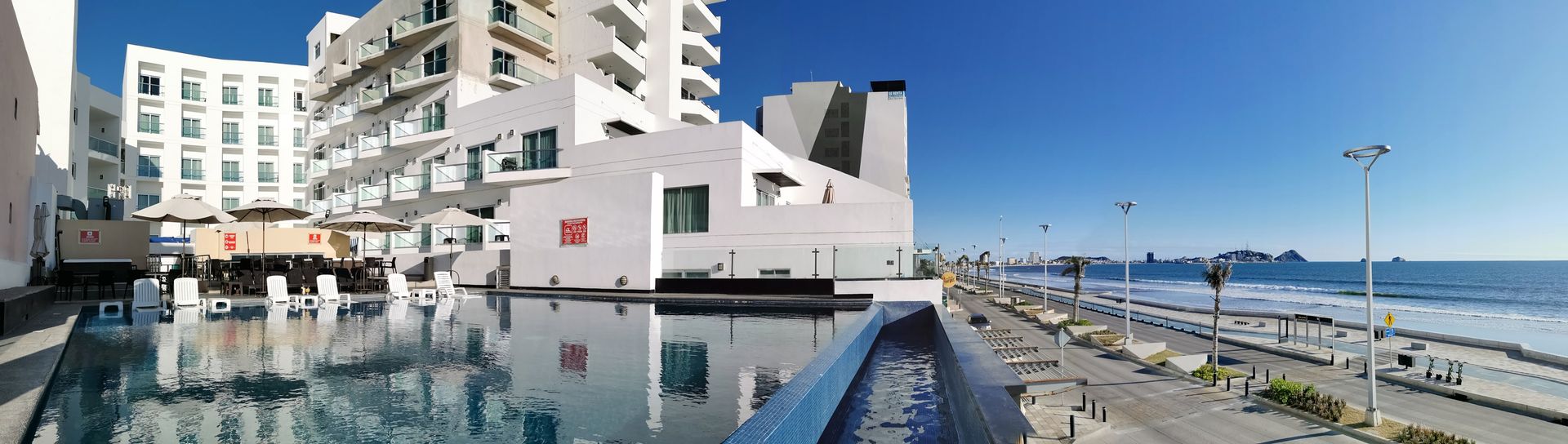 Hay una gran piscina frente a un hotel.