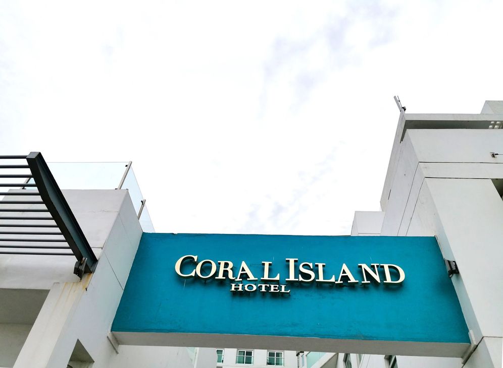 El hotel Coral Island tiene un cartel azul en el costado del edificio.