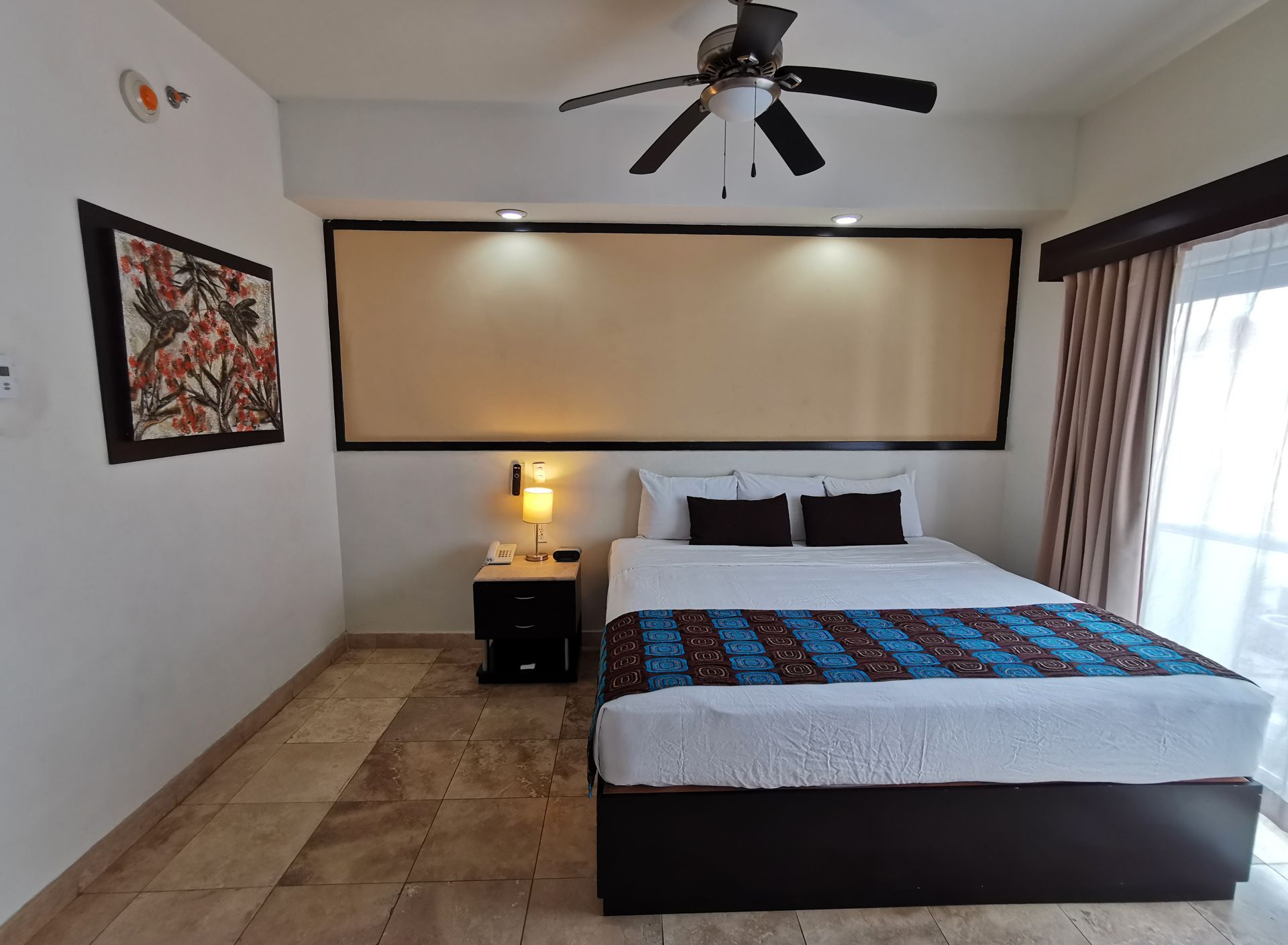 Una habitación de hotel con una cama grande y un ventilador de techo.