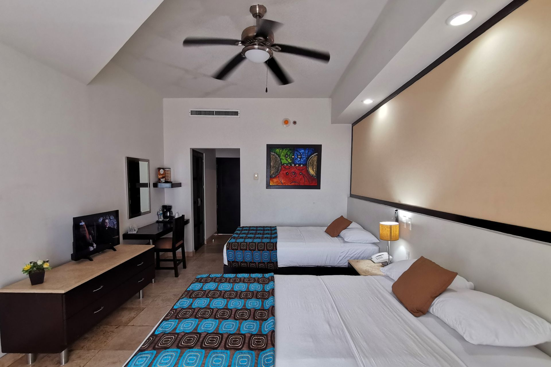 Una habitación de hotel con dos camas y un ventilador de techo.