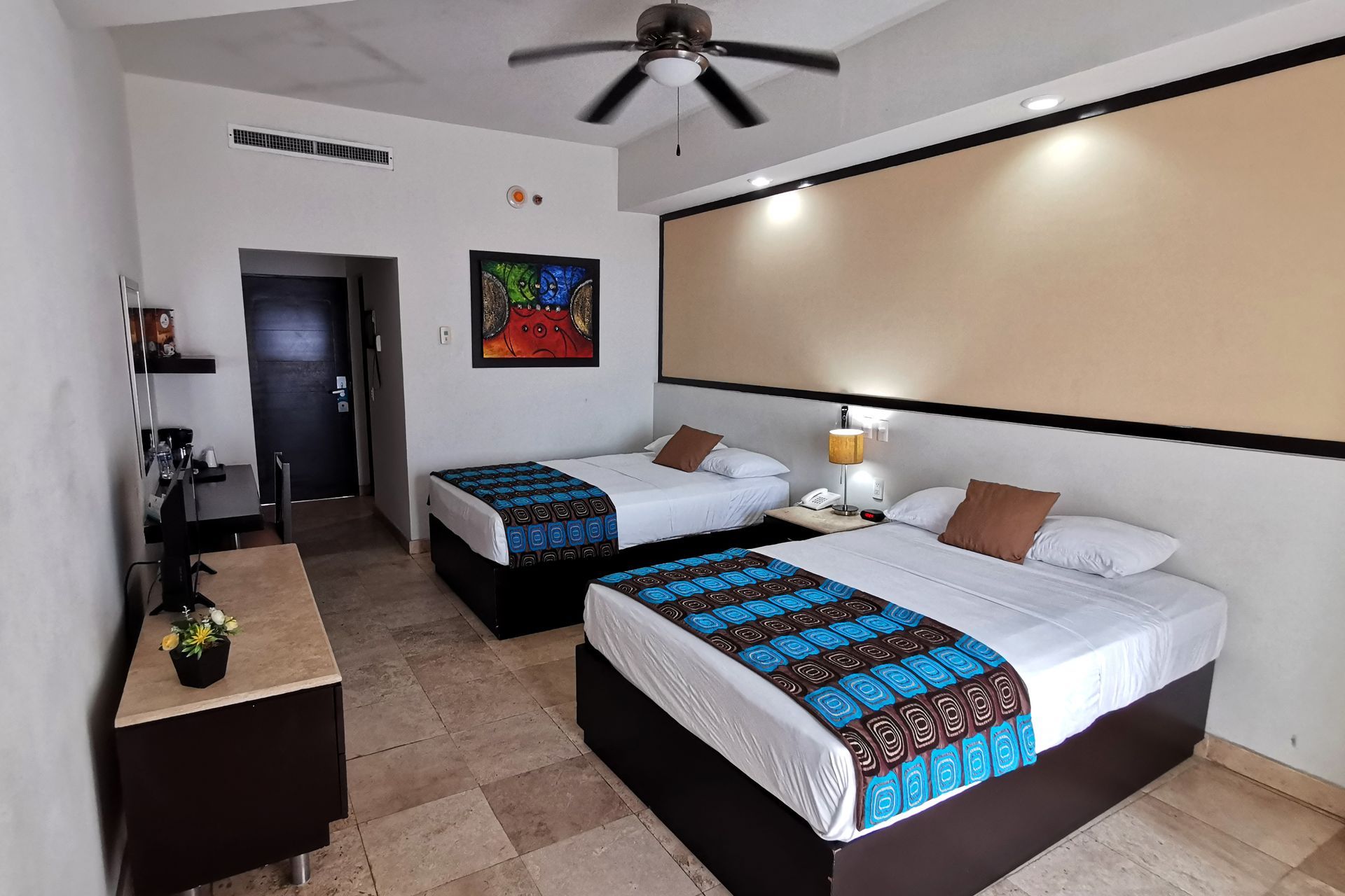 Una habitación de hotel con dos camas y un ventilador de techo.