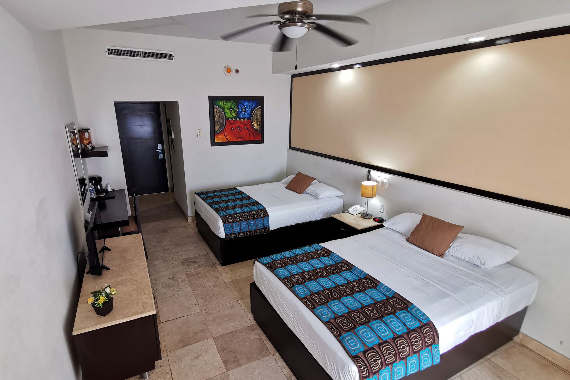 Una habitación de hotel con dos camas y un ventilador de techo.