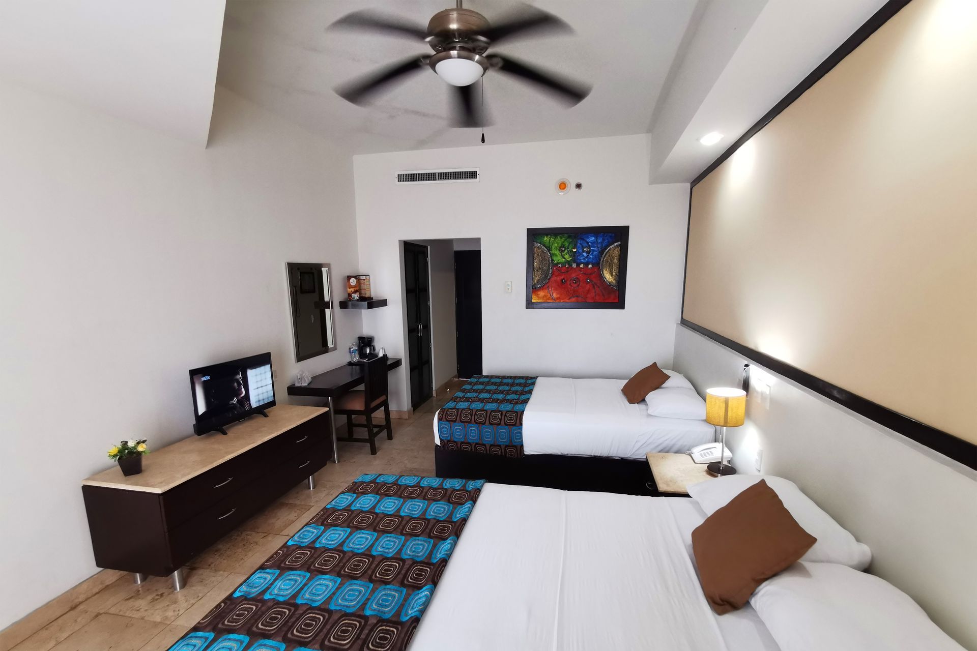 Una habitación de hotel con dos camas y un ventilador de techo.