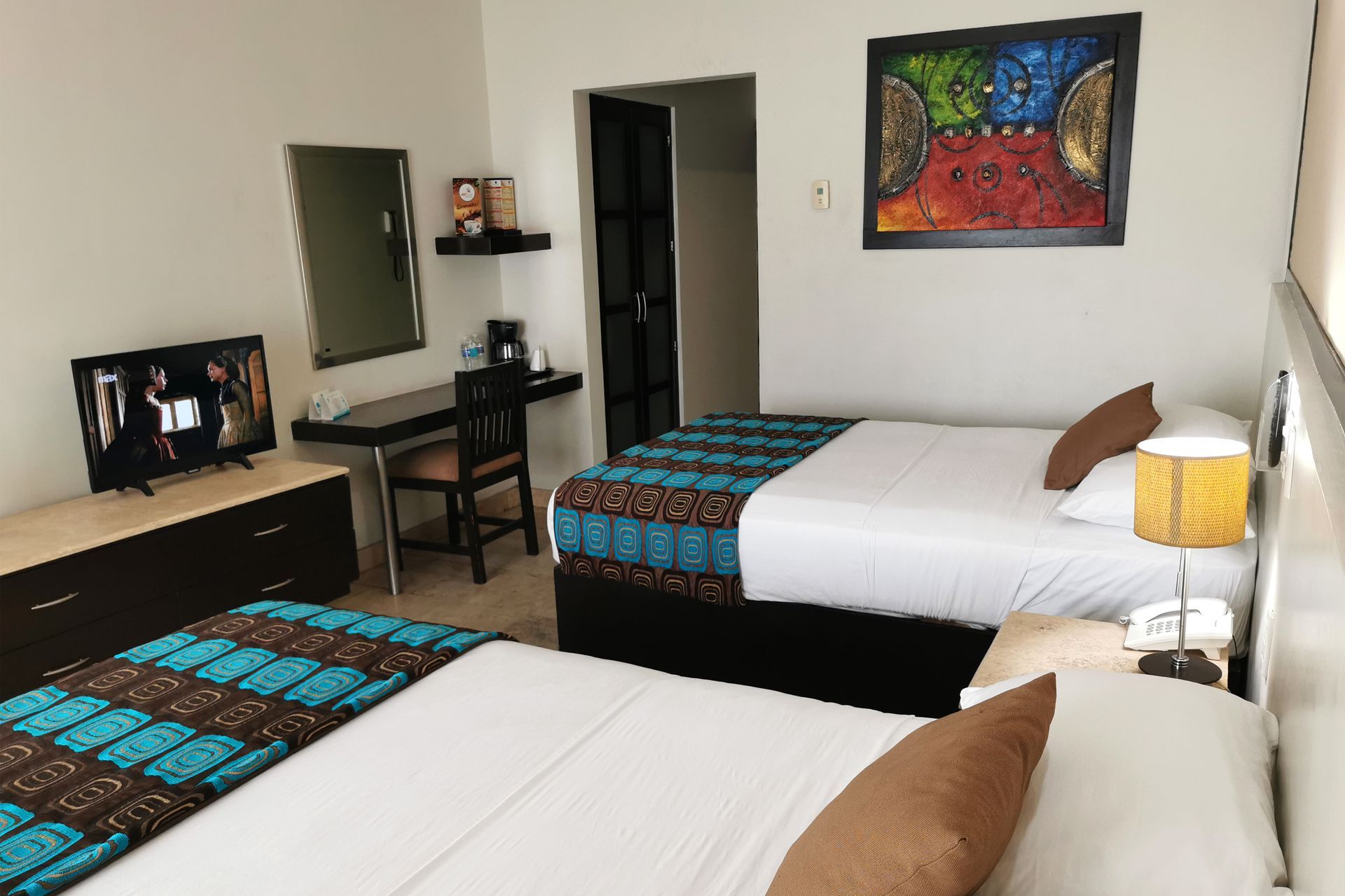 Una habitación de hotel con dos camas, un escritorio y un televisor.