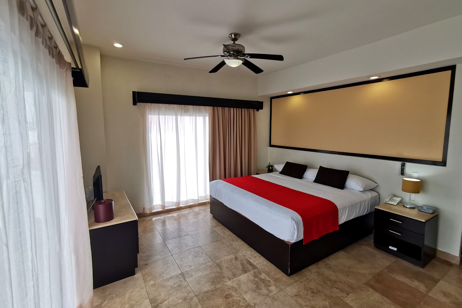 Una habitación de hotel con una cama tamaño king y un ventilador de techo.