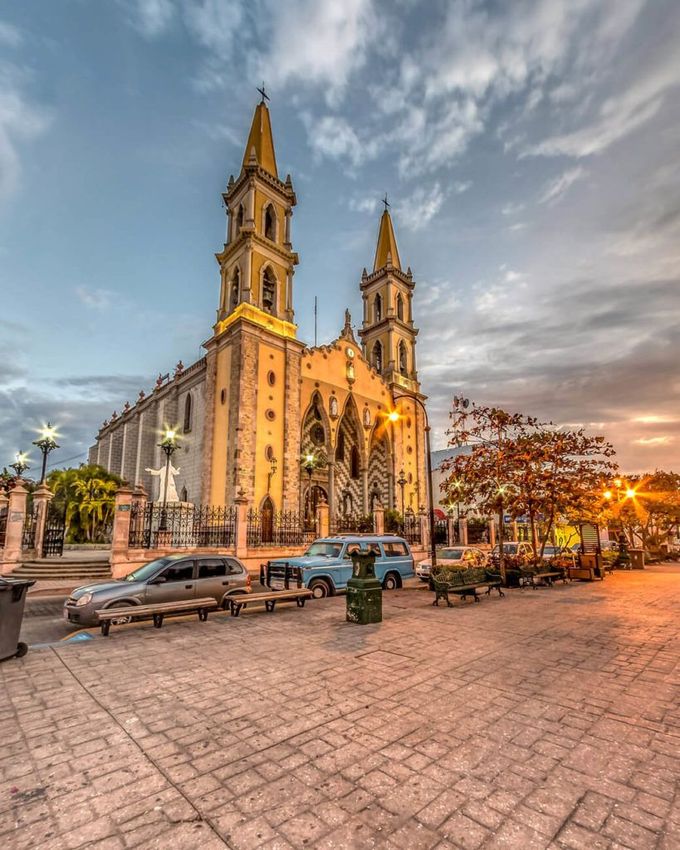 Una iglesia grande con muchos coches aparcados delante de ella.