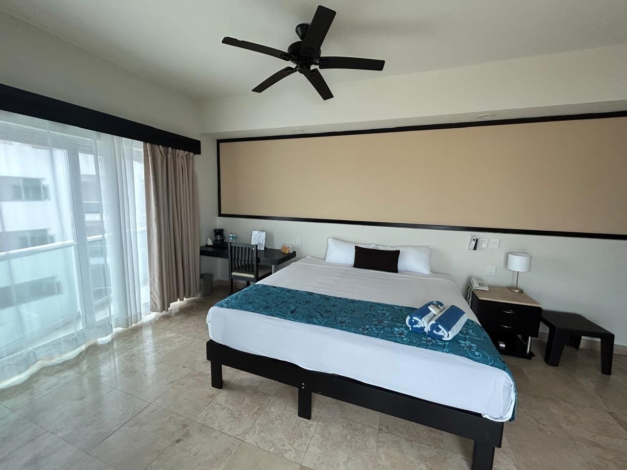 Una habitación de hotel con una cama grande y un balcón con vista al océano.