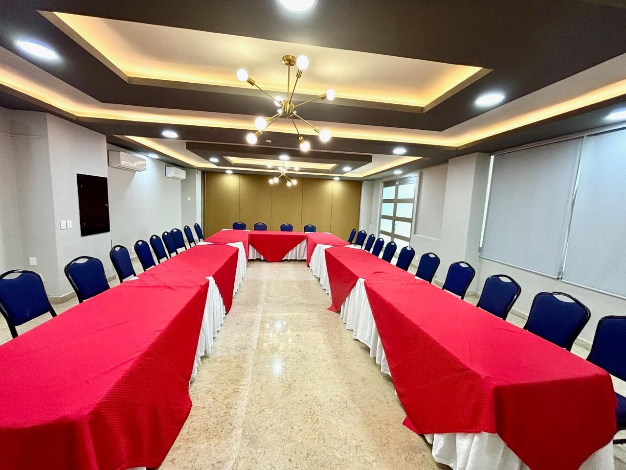 Una gran sala de conferencias con mesas rojas y sillas azules.