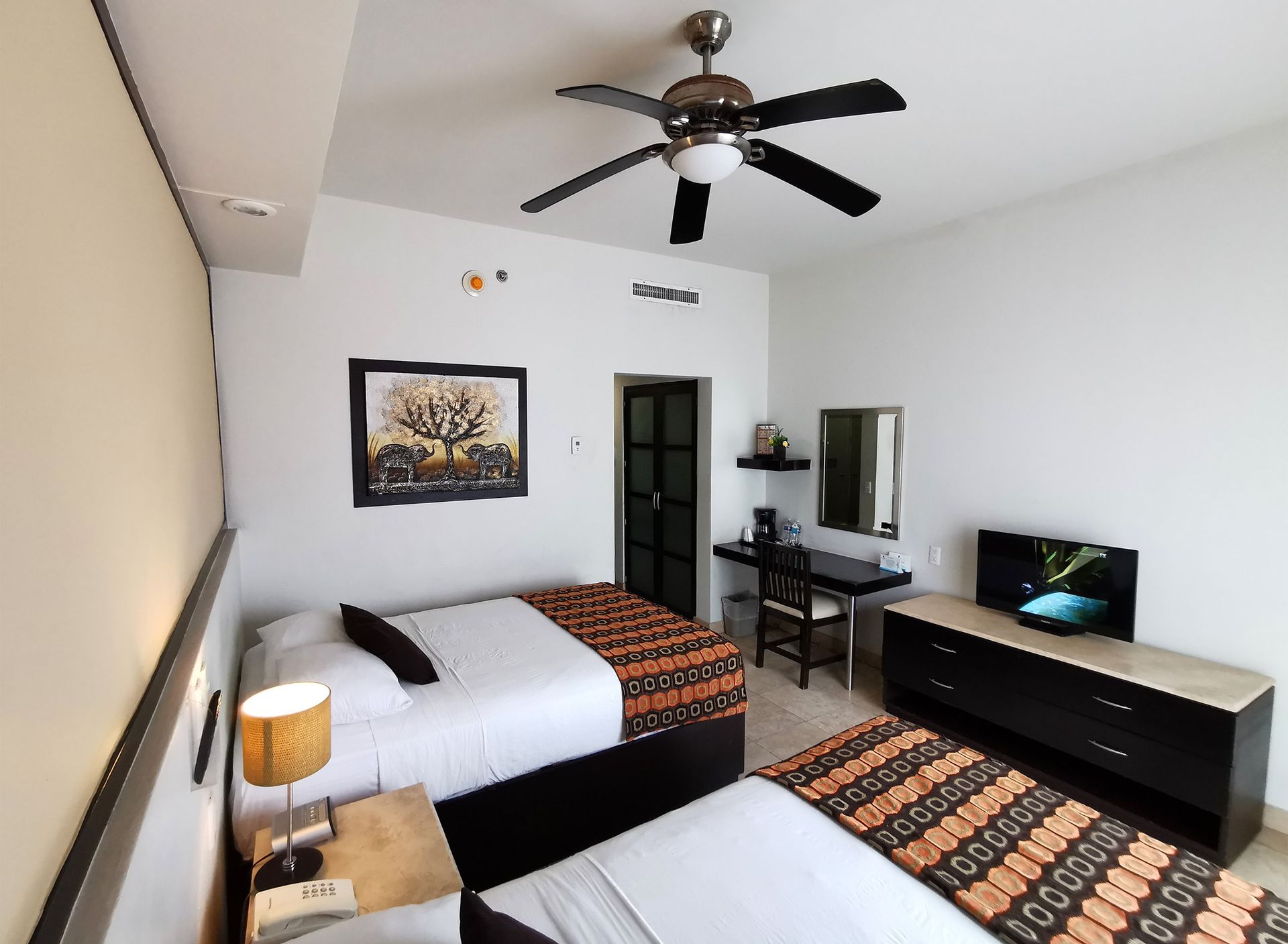 Una habitación de hotel con dos camas y un ventilador de techo.