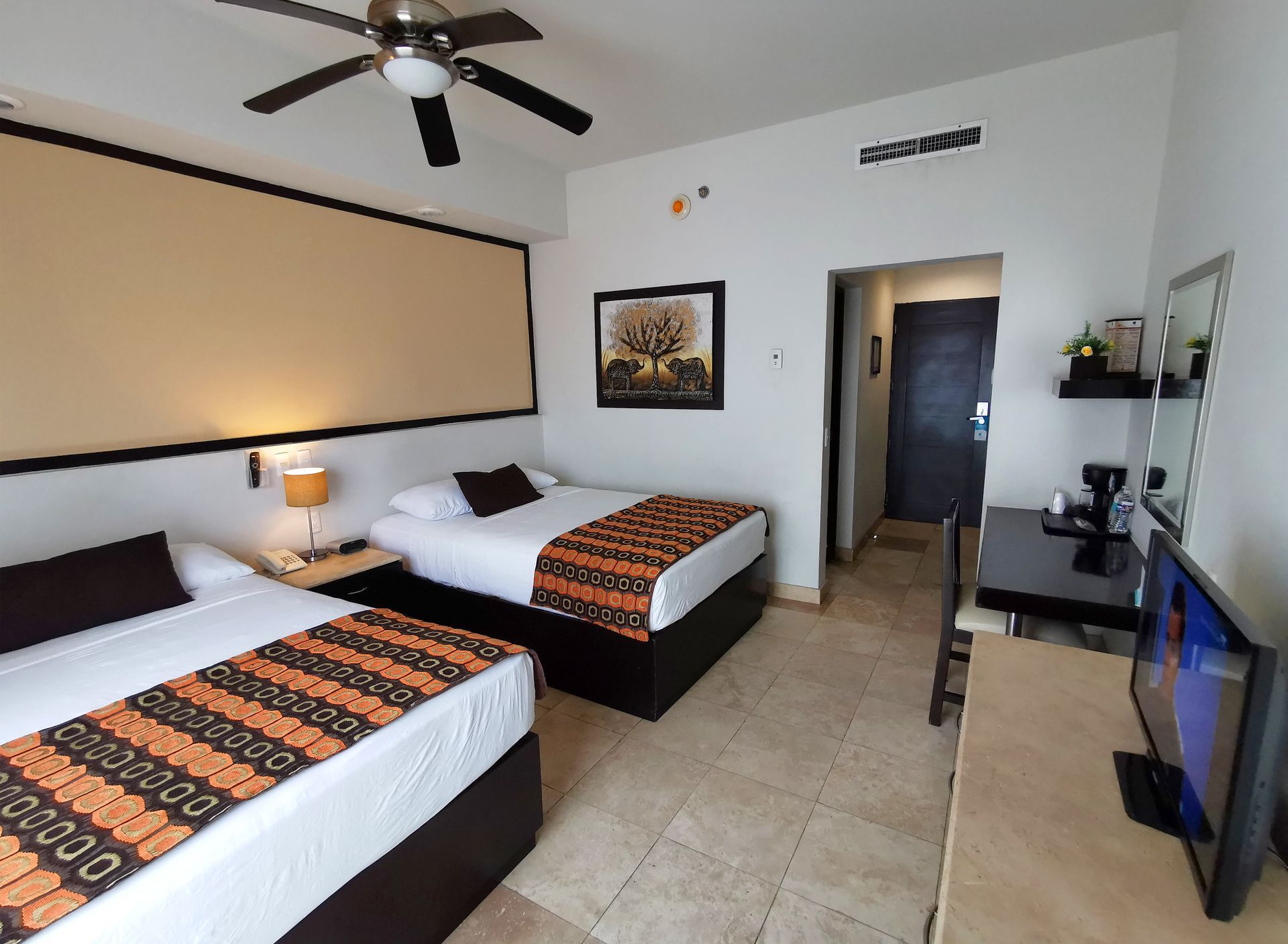 Una habitación de hotel con dos camas y un televisor de pantalla plana.