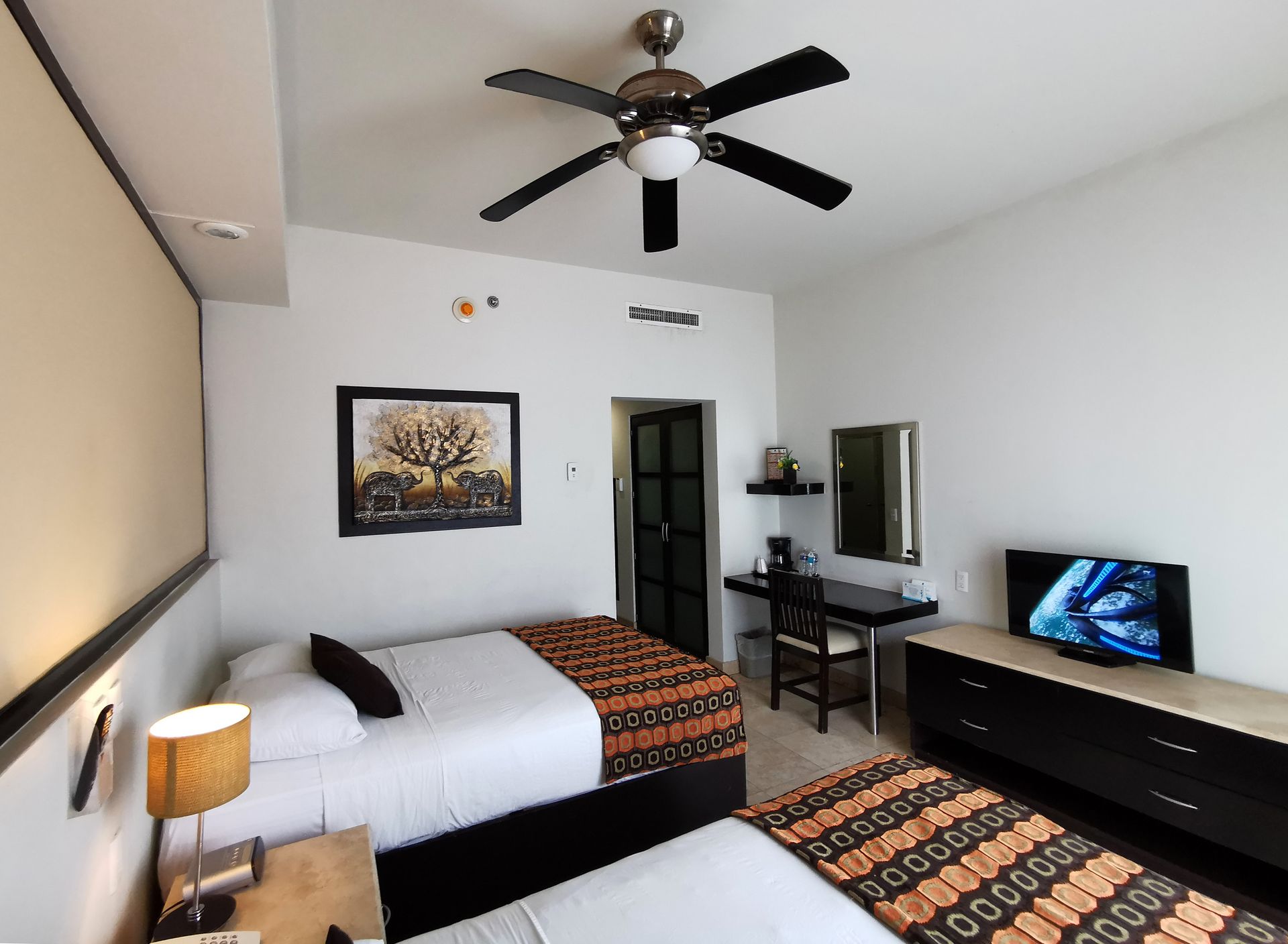 Una habitación de hotel con dos camas y un ventilador de techo.