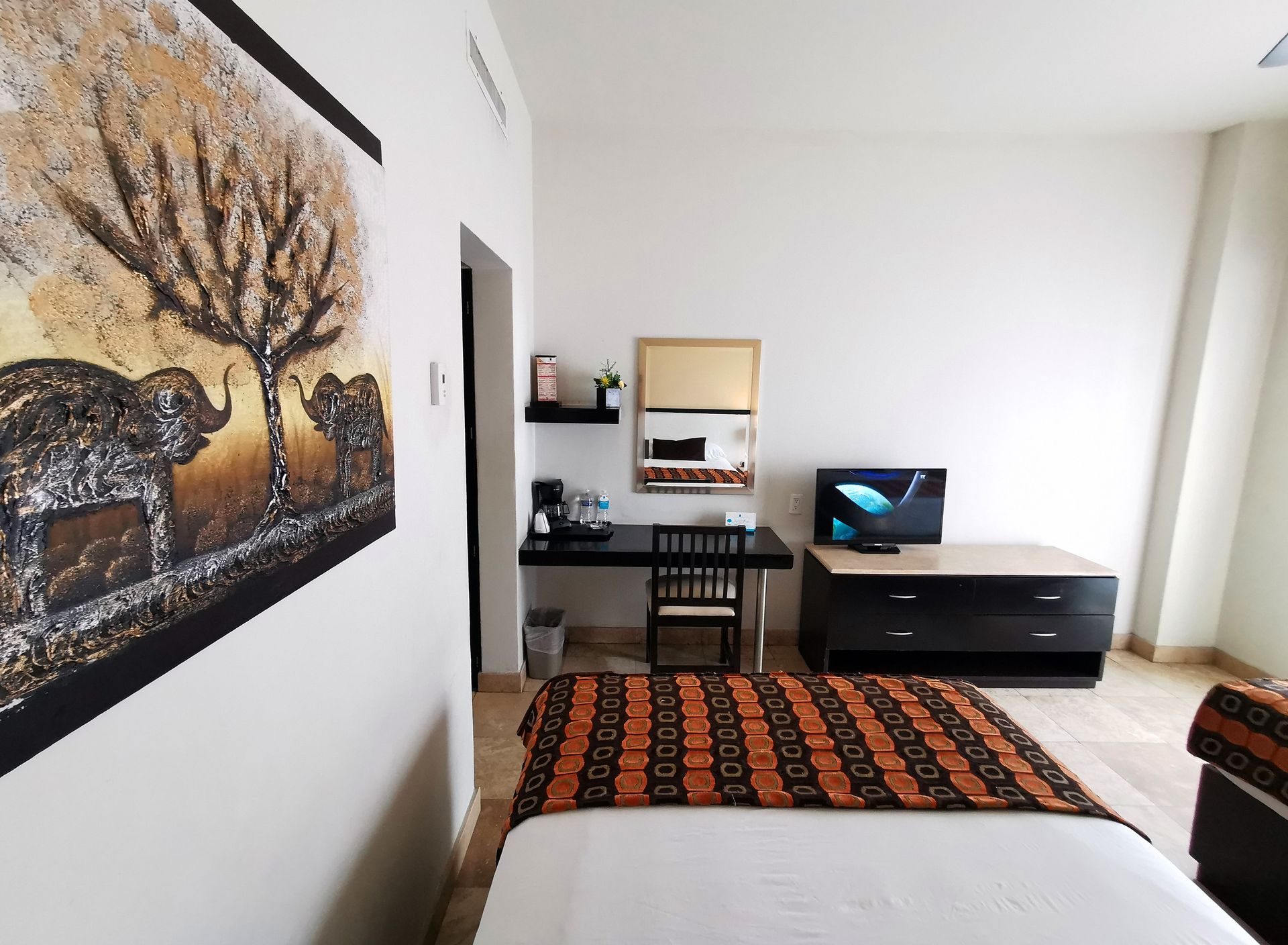 Un dormitorio con un cuadro de elefantes en la pared.