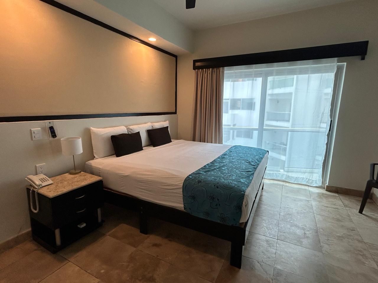 Una habitación de hotel con una cama grande y un ventilador de techo.