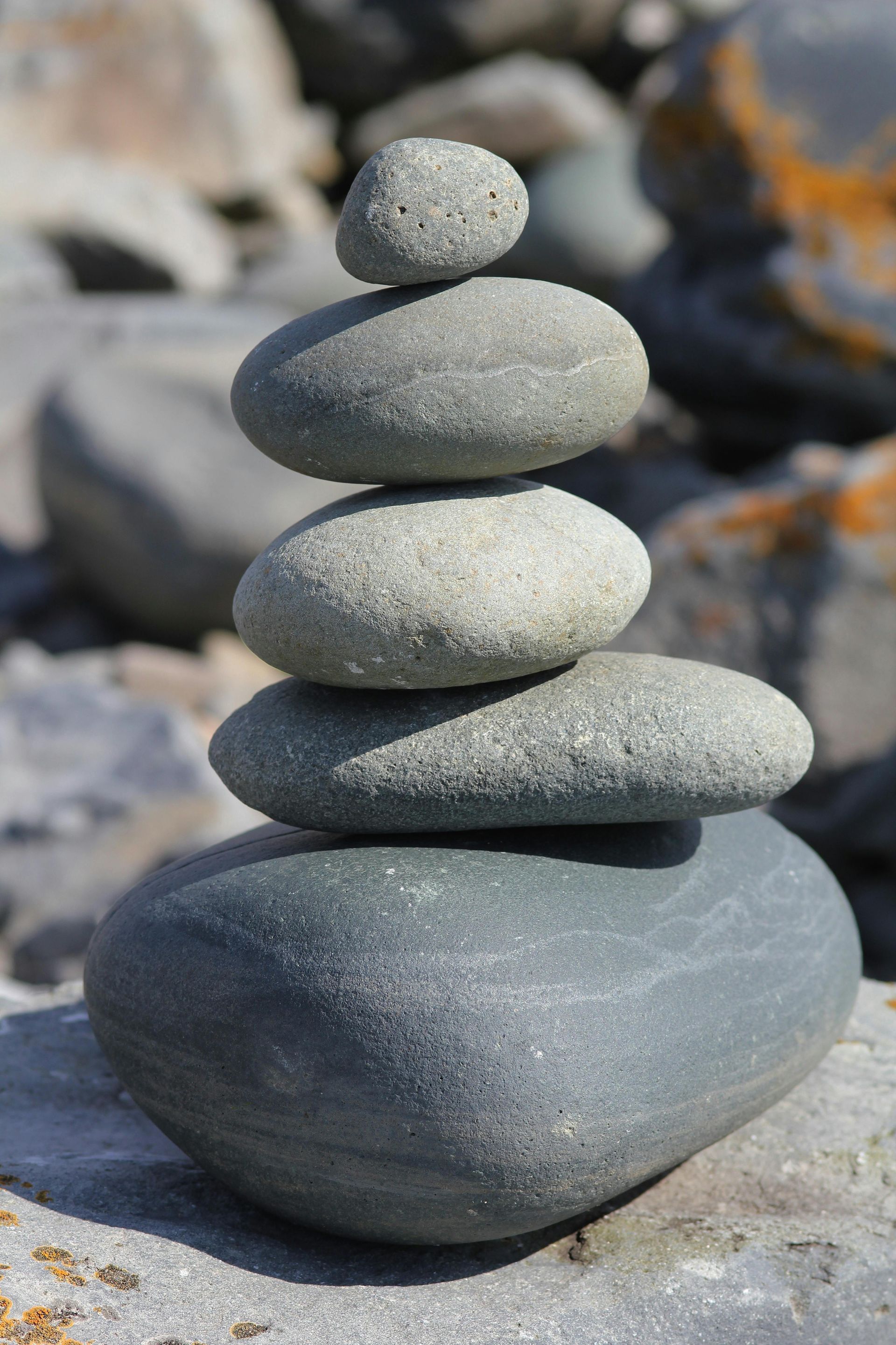 Stacked gray stones, resembling a cairn, on a blurred rocky background.