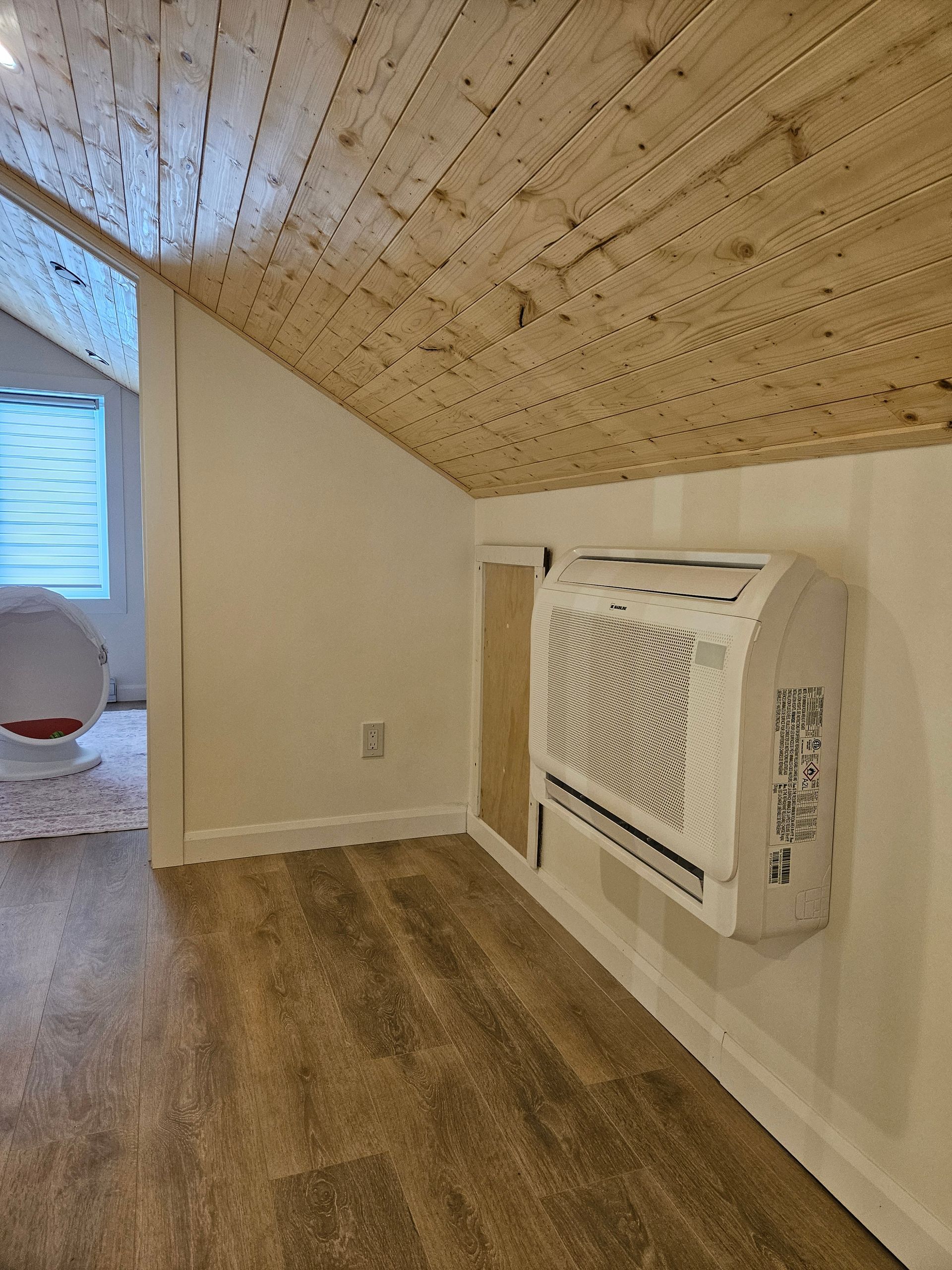 Une pièce avec un plafond en bois et un climatiseur mural.