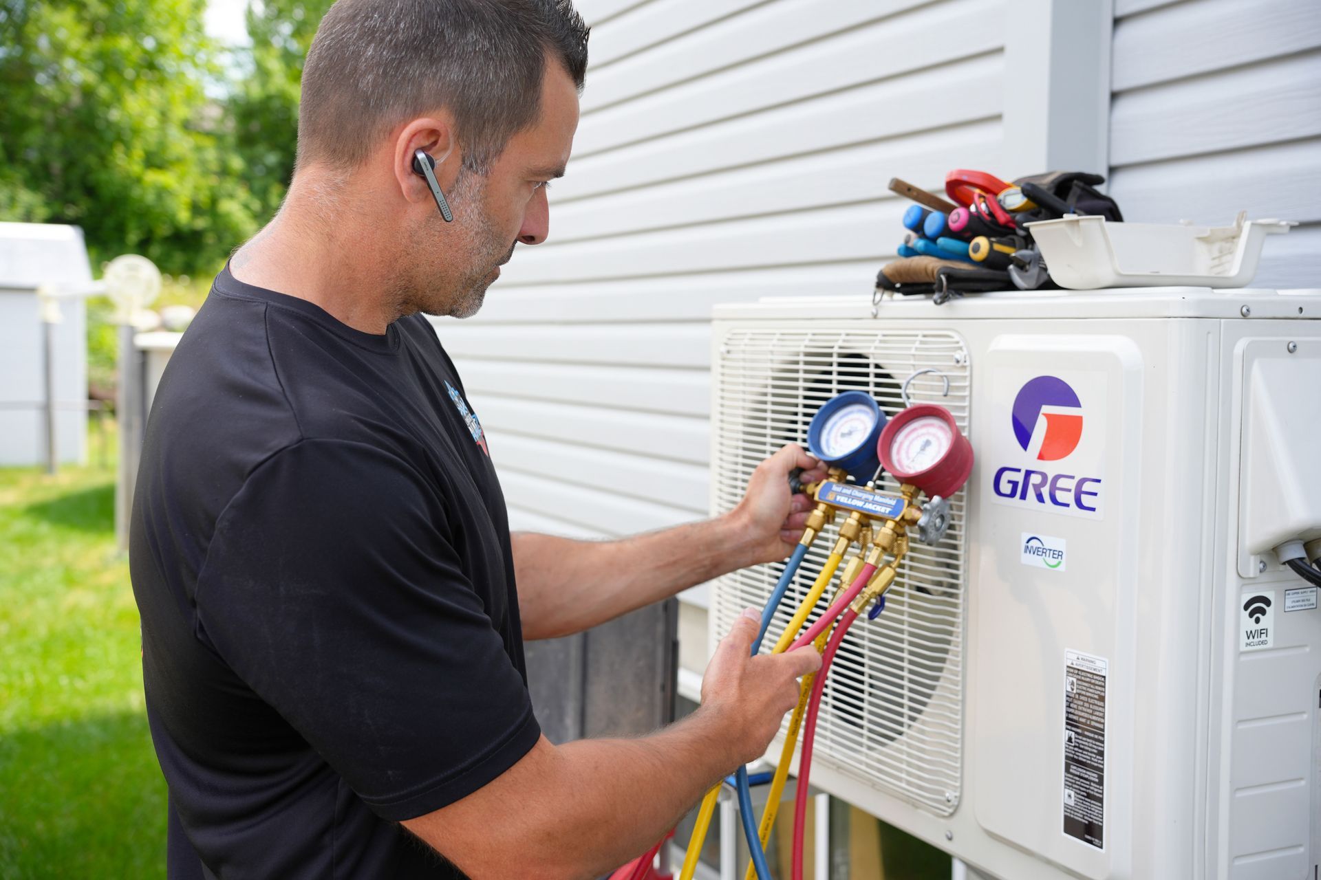 Un homme travaille sur un climatiseur à l'extérieur d'une maison.