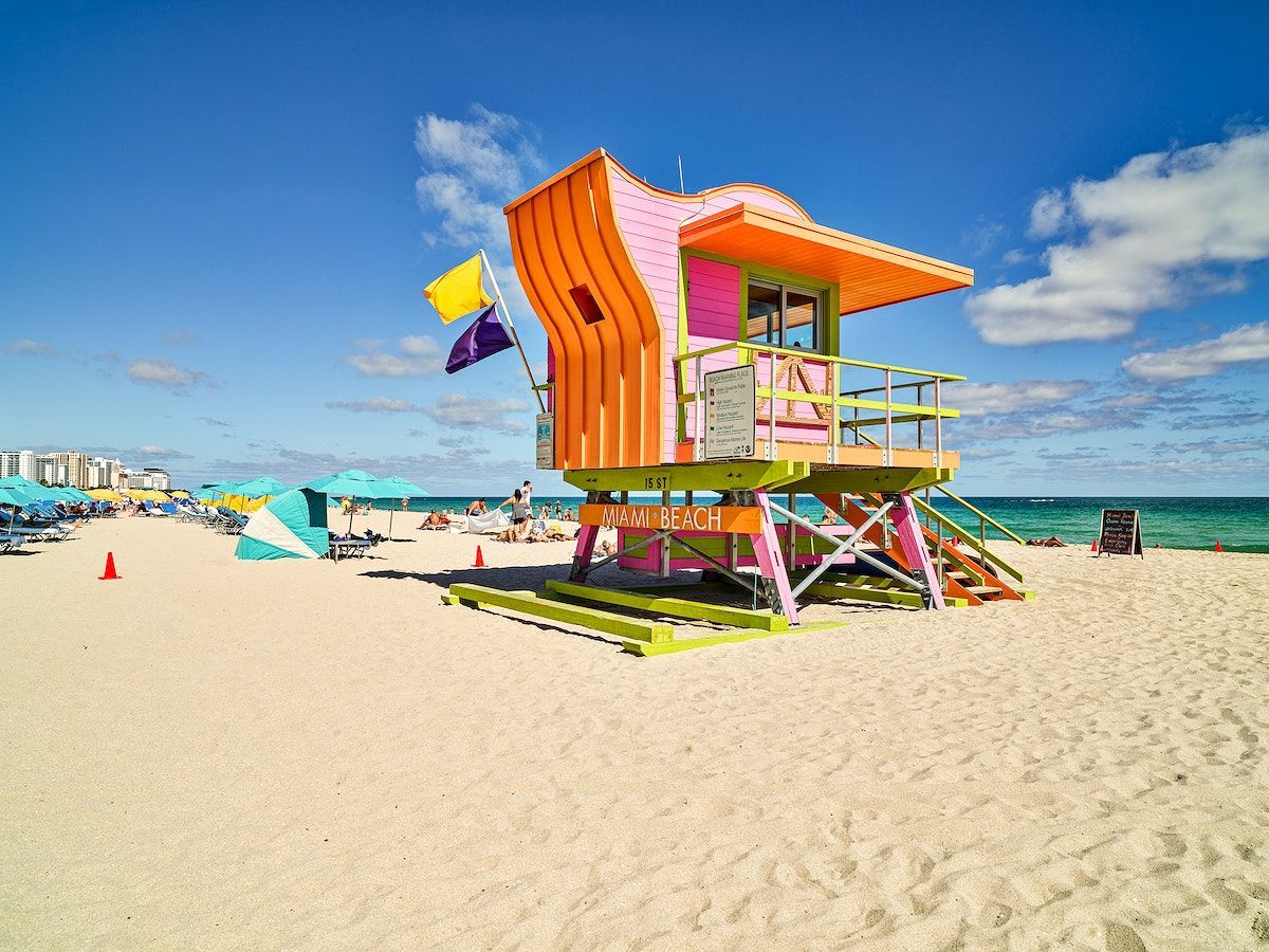 A colorful lifeguard tower is sitting on top of a sandy beach.