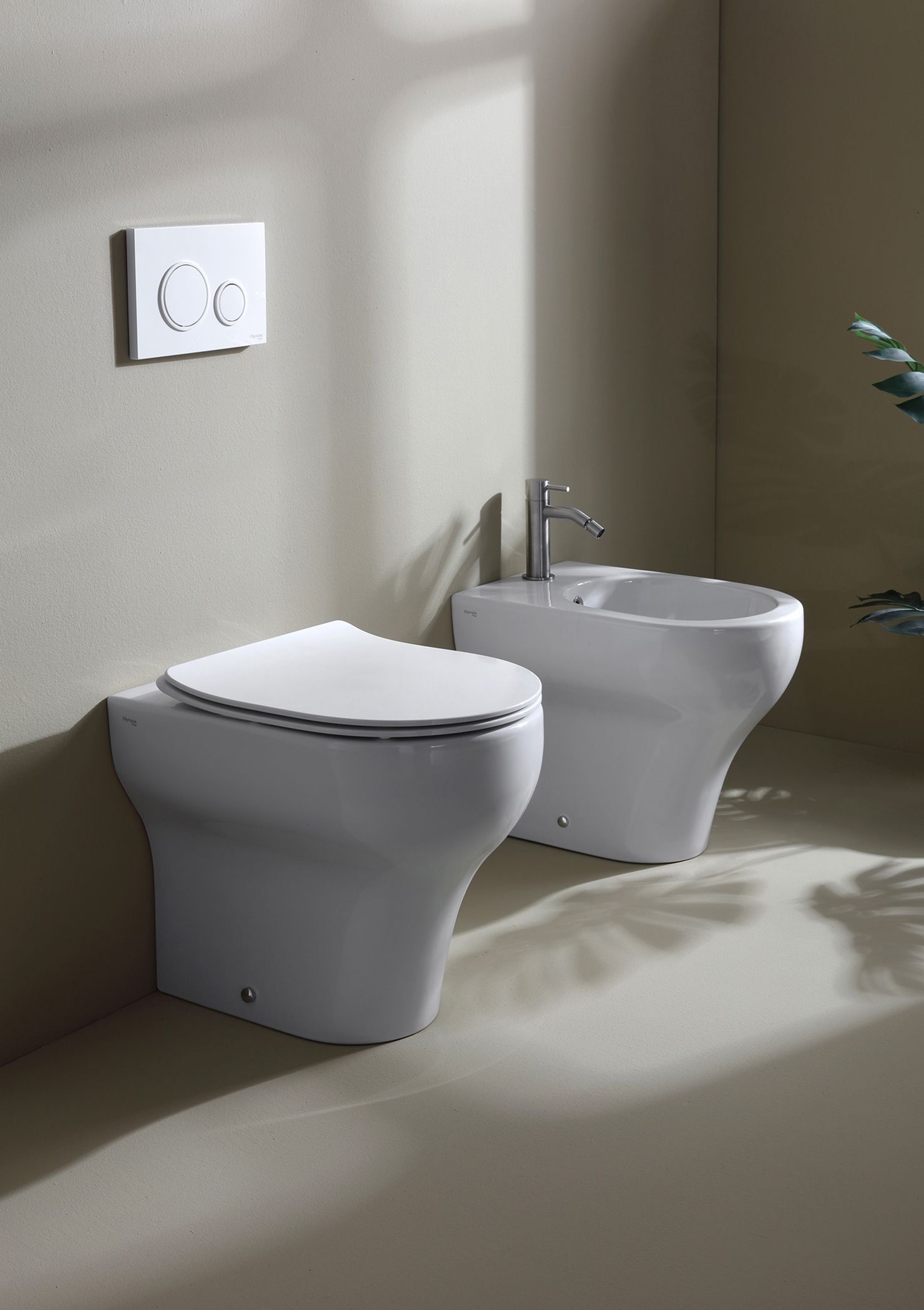 WC e bidet bianchi sospesi in un bagno con placca di scarico.