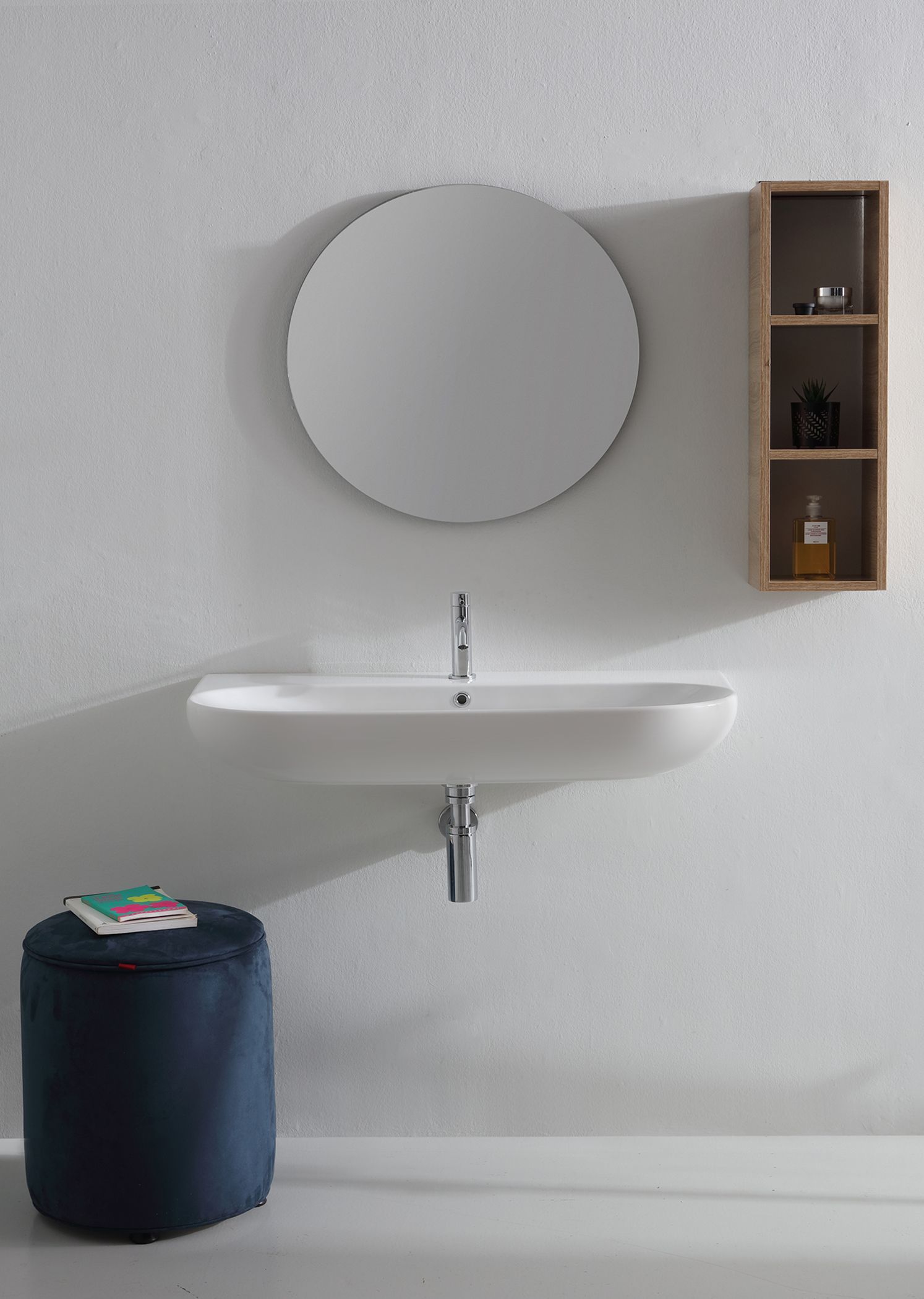 Lavandino bianco del bagno con specchio, mensola in legno e pouf blu contro una parete strutturata.