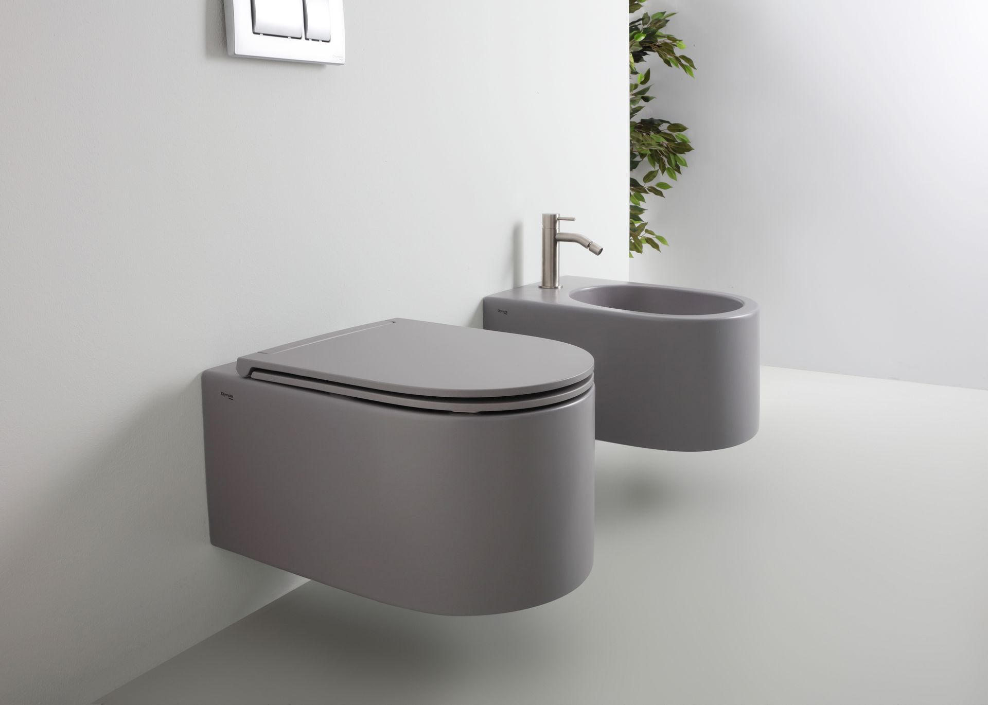 WC e bidet grigi sospesi in un bagno minimalista. Il bidet è dotato di un rubinetto argentato.