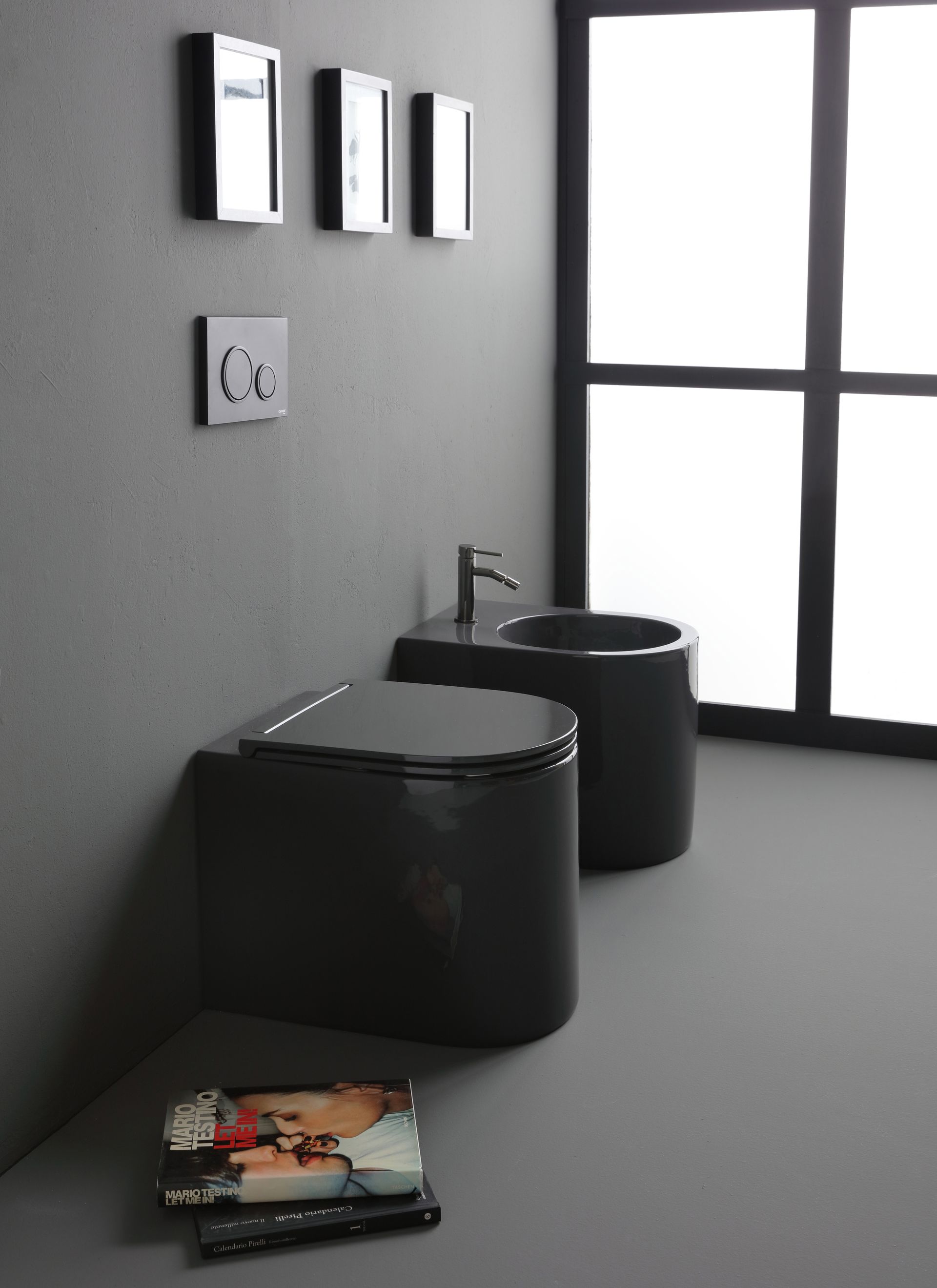 WC e bidet grigio scuro in un bagno moderno con una grande finestra e quadri incorniciati alla parete.
