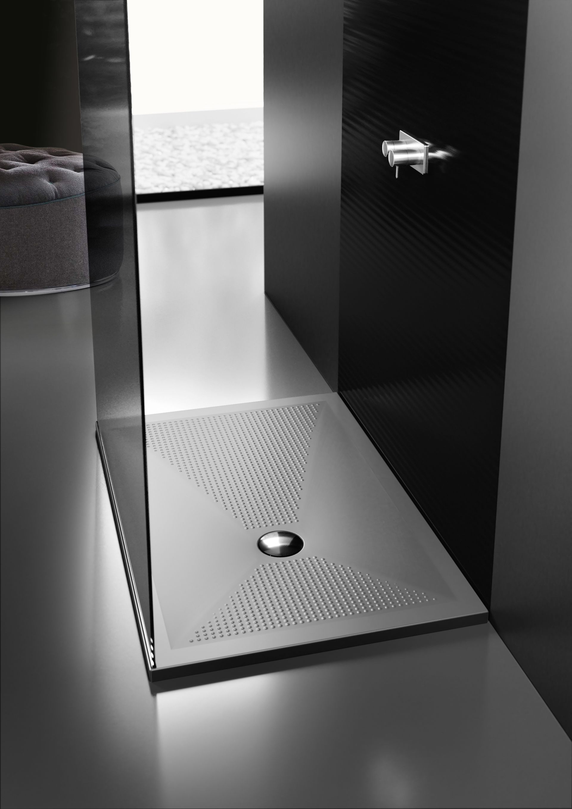 Elegante cabina doccia nera con pavimento strutturato, scarico e rubinetto a parete, in un bagno moderno.