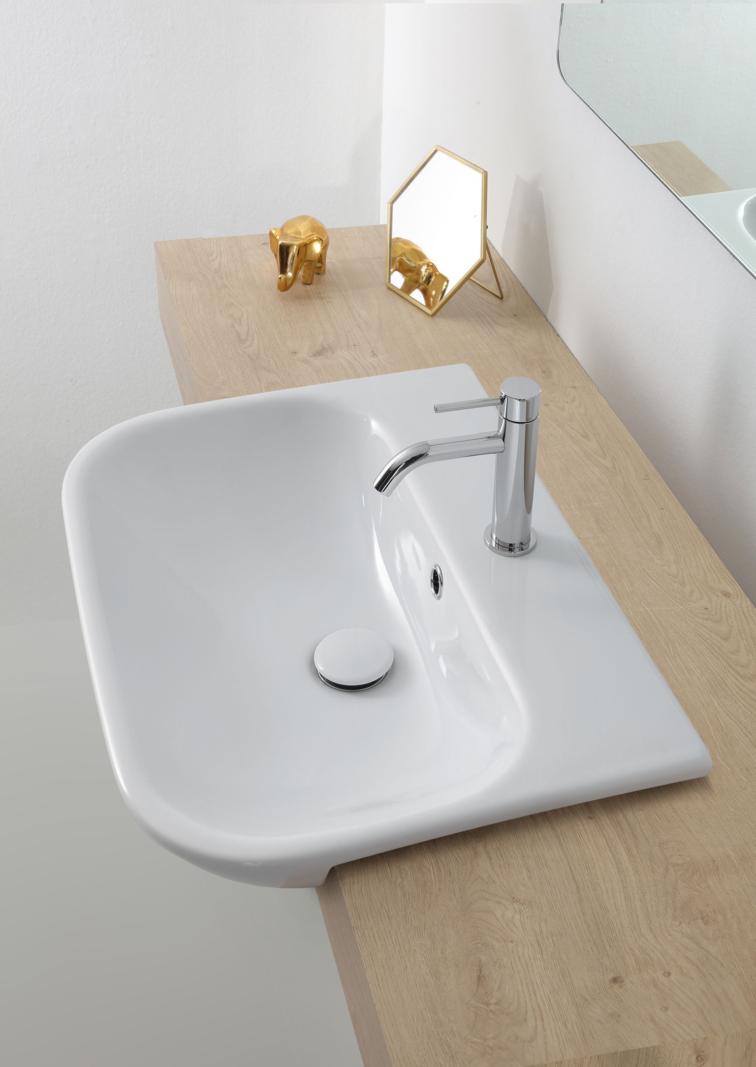 Lavandino bianco con rubinetto cromato, su un piano di lavoro beige, con specchio e dettagli dorati.
