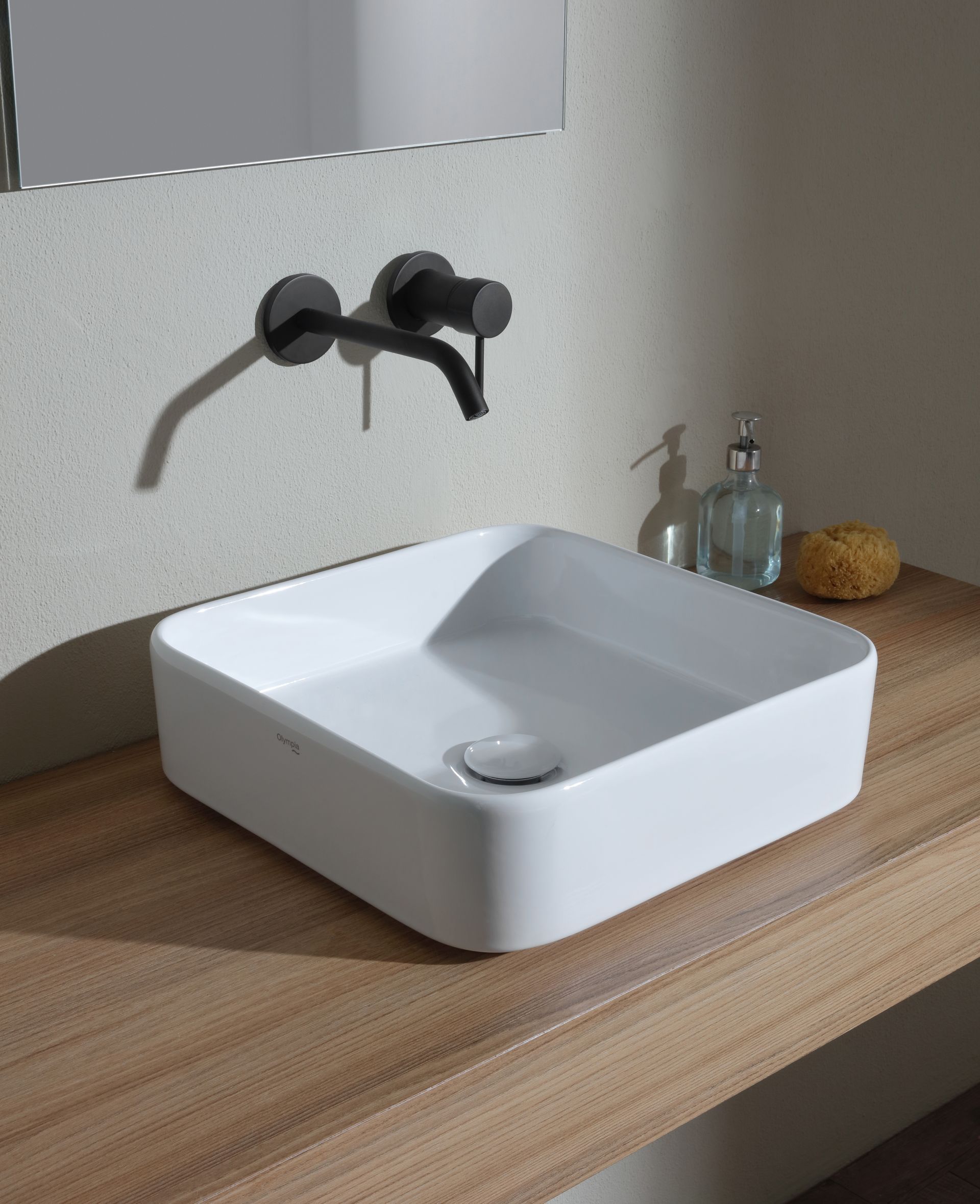 Lavandino quadrato bianco con rubinetto nero su un piano in legno.