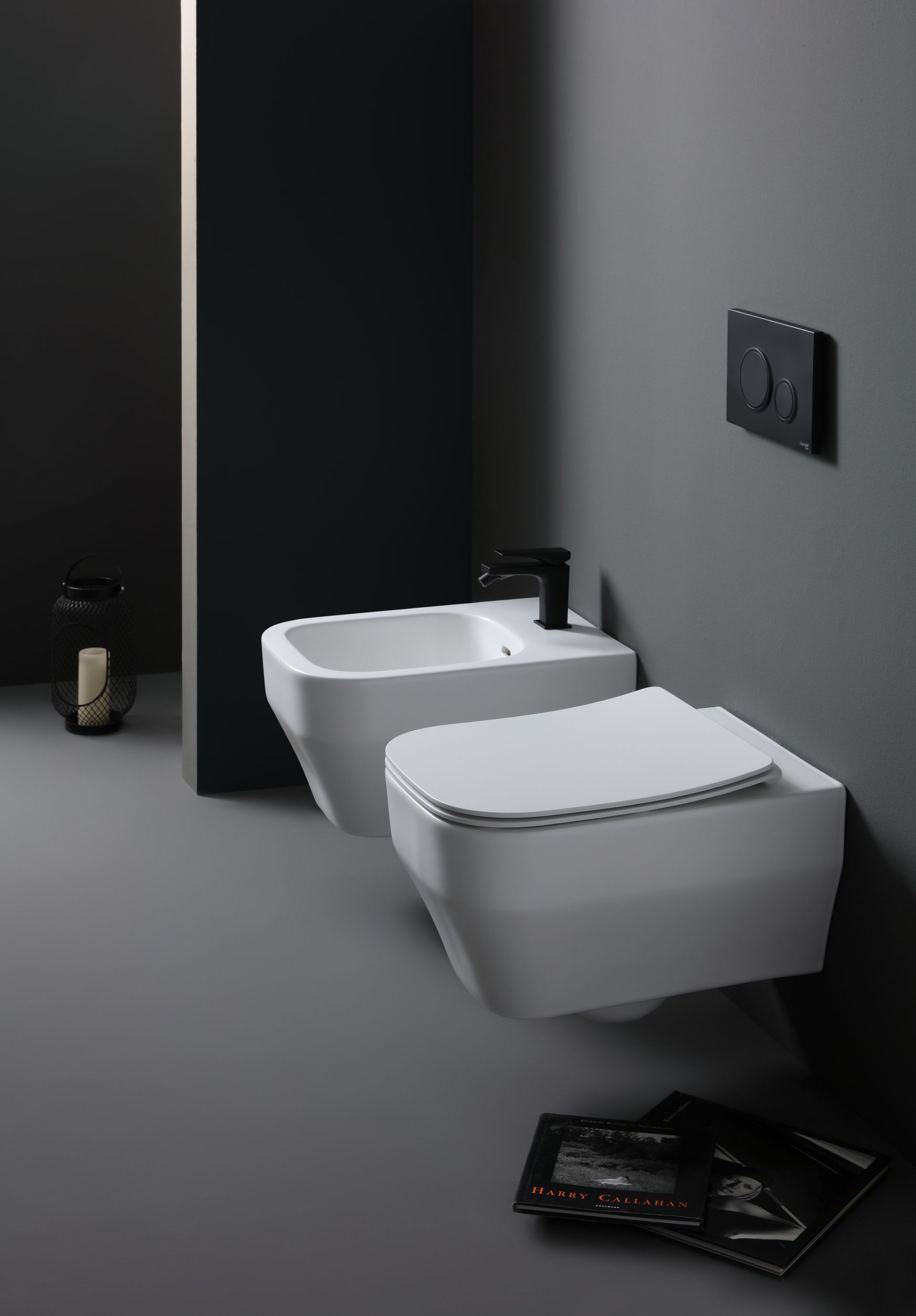 WC e bidet bianchi sospesi in un bagno minimalista con pareti grigio scuro.