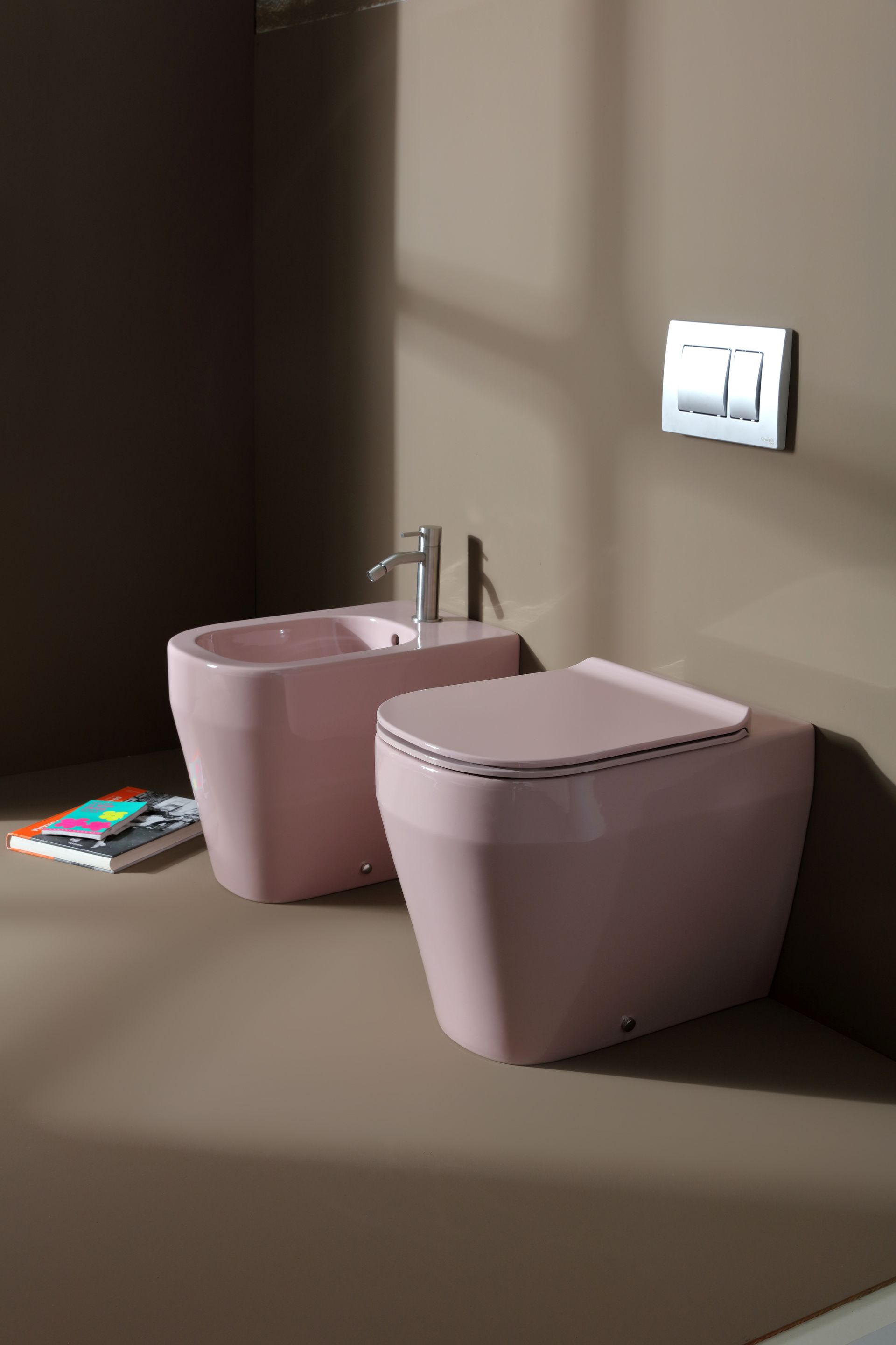 WC e bidet rosa in un bagno moderno. Pulsante di scarico a parete in alto.
