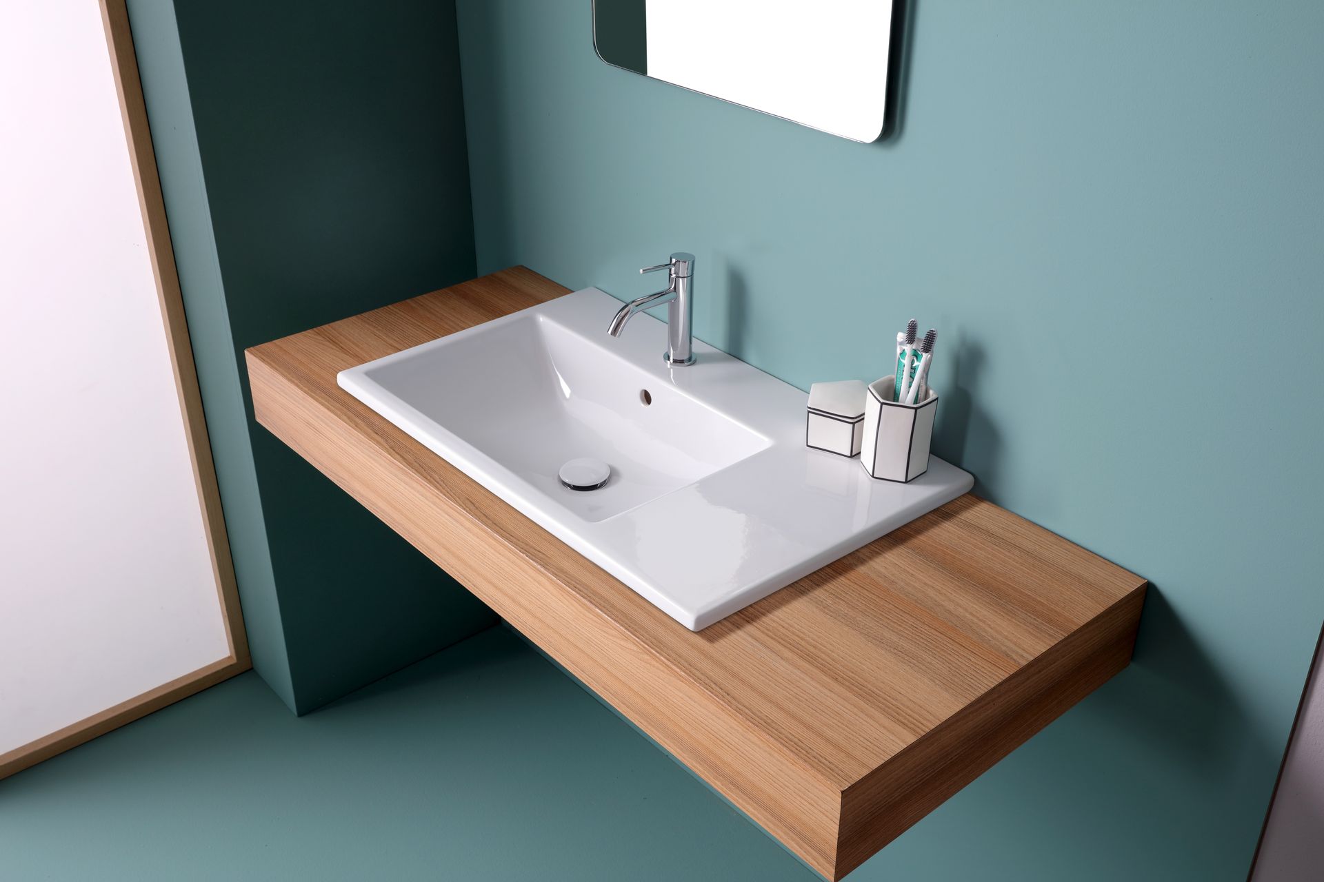 Lavandino da bagno su un ripiano in legno con specchio. Parete verde acqua, lavandino bianco con rubinetto e specchio.