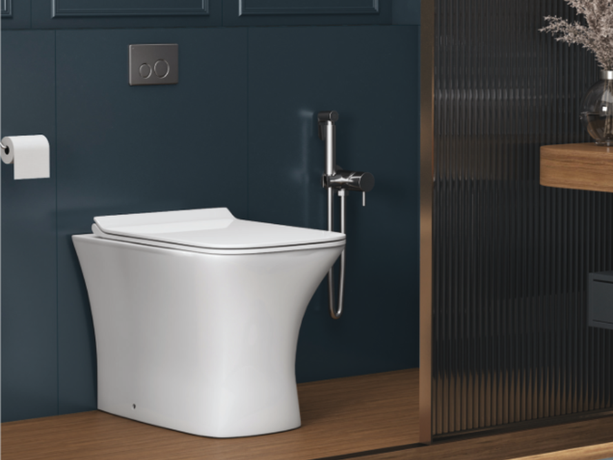 White modern toilet in a bathroom with blue wall, bidet, and wooden floor.