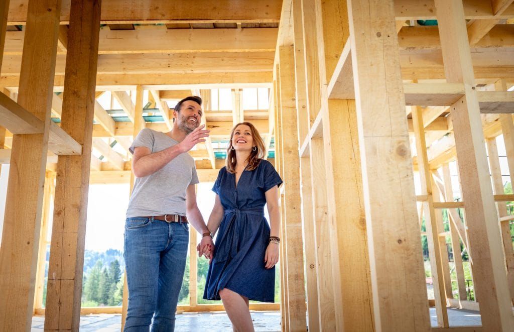 A man and a woman are holding hands in a house under construction.