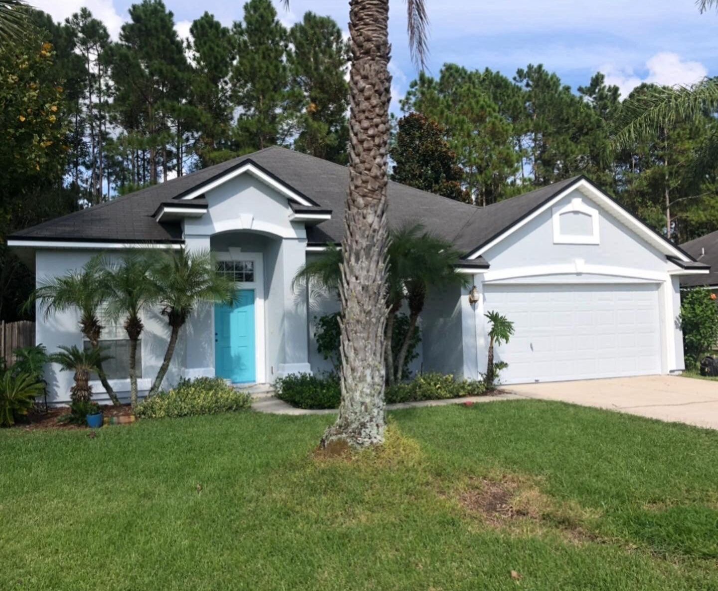 A white house with a blue door and a palm tree in front of it