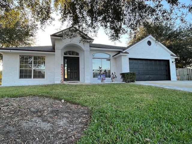 A white house with a black garage door is sitting on top of a lush green lawn.